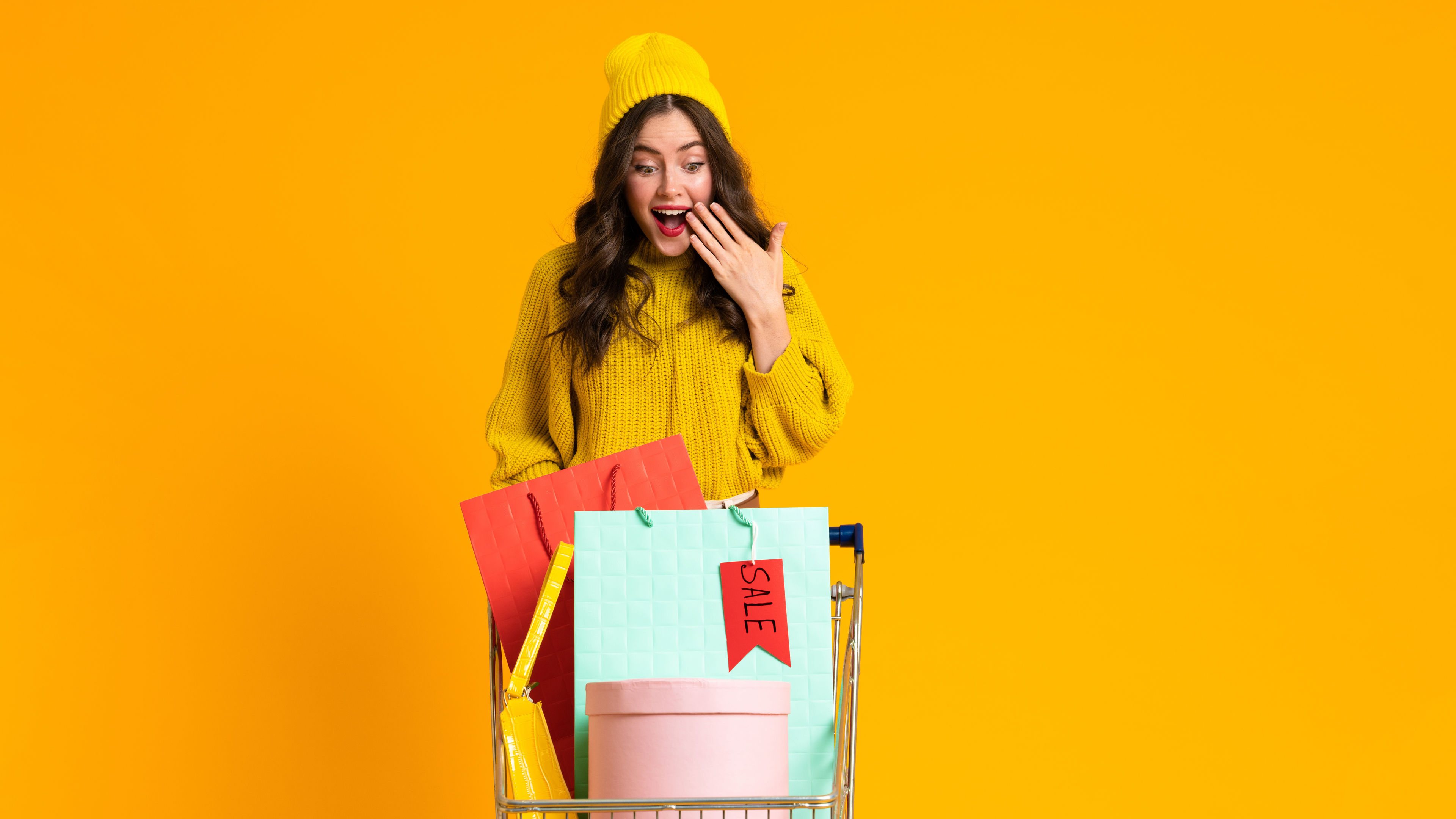 Excited woman expressing surprise while posing with shopping cart