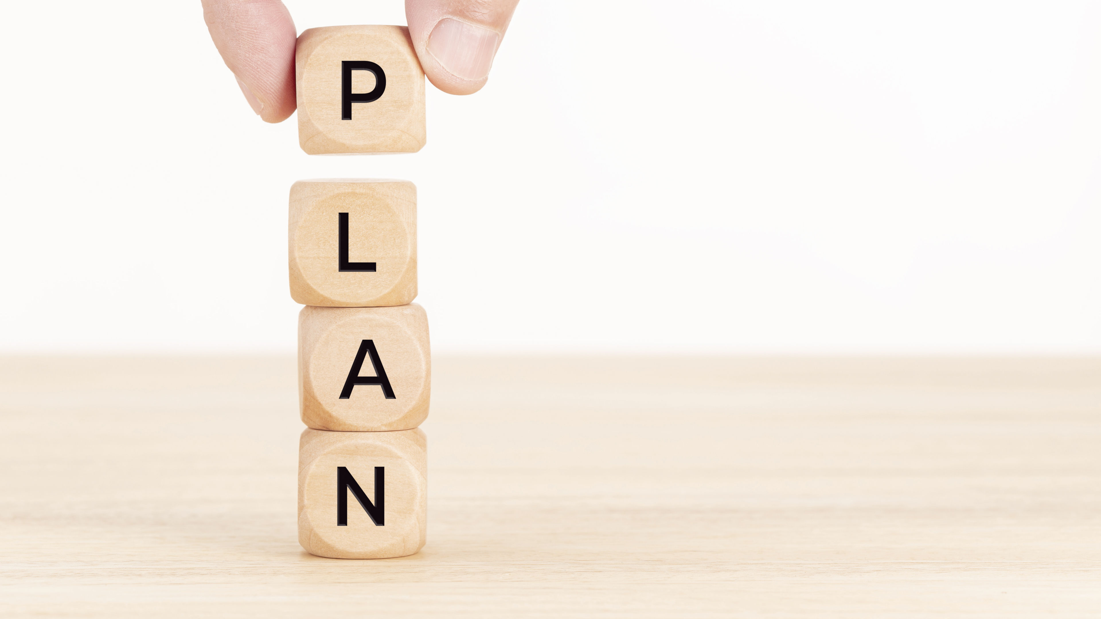 Plan concept. Hand holding a Wooden block with text on table 