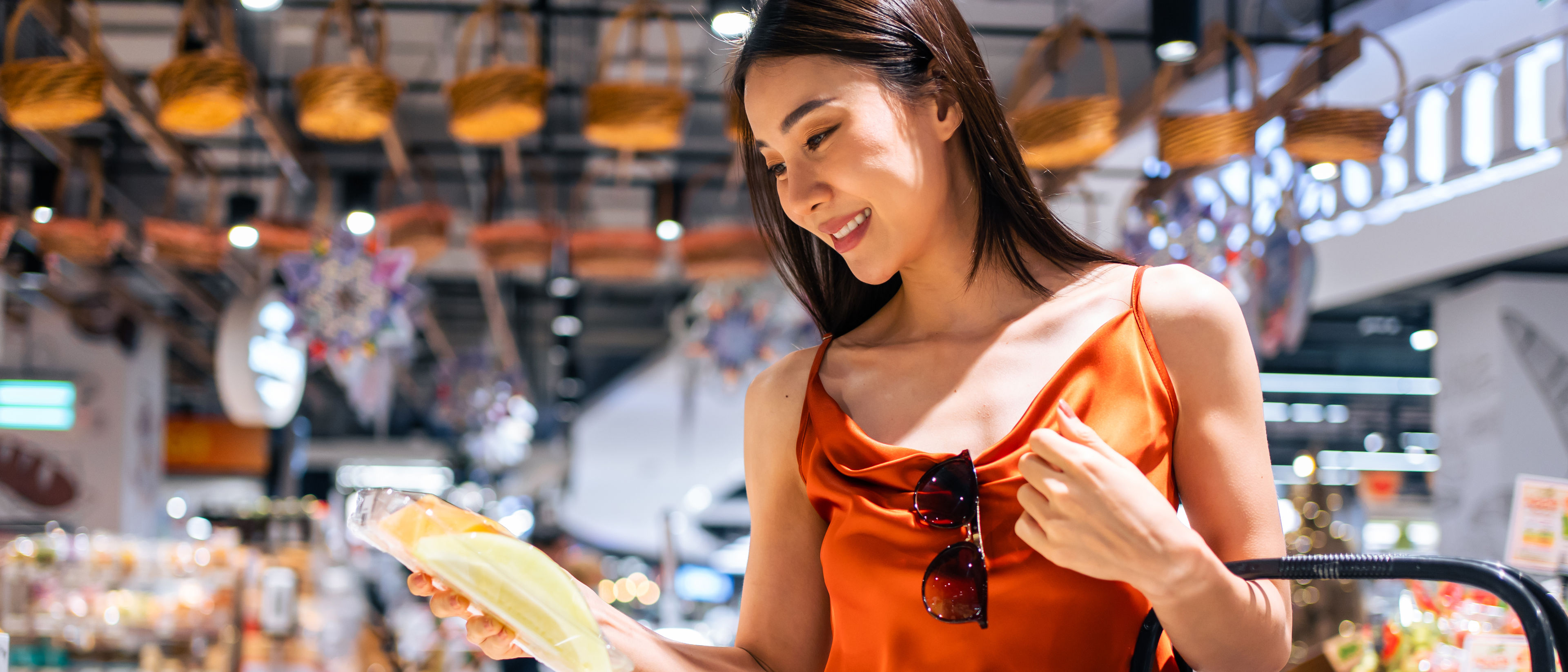 Asian young beautiful woman holding grocery basket walk in supermarket