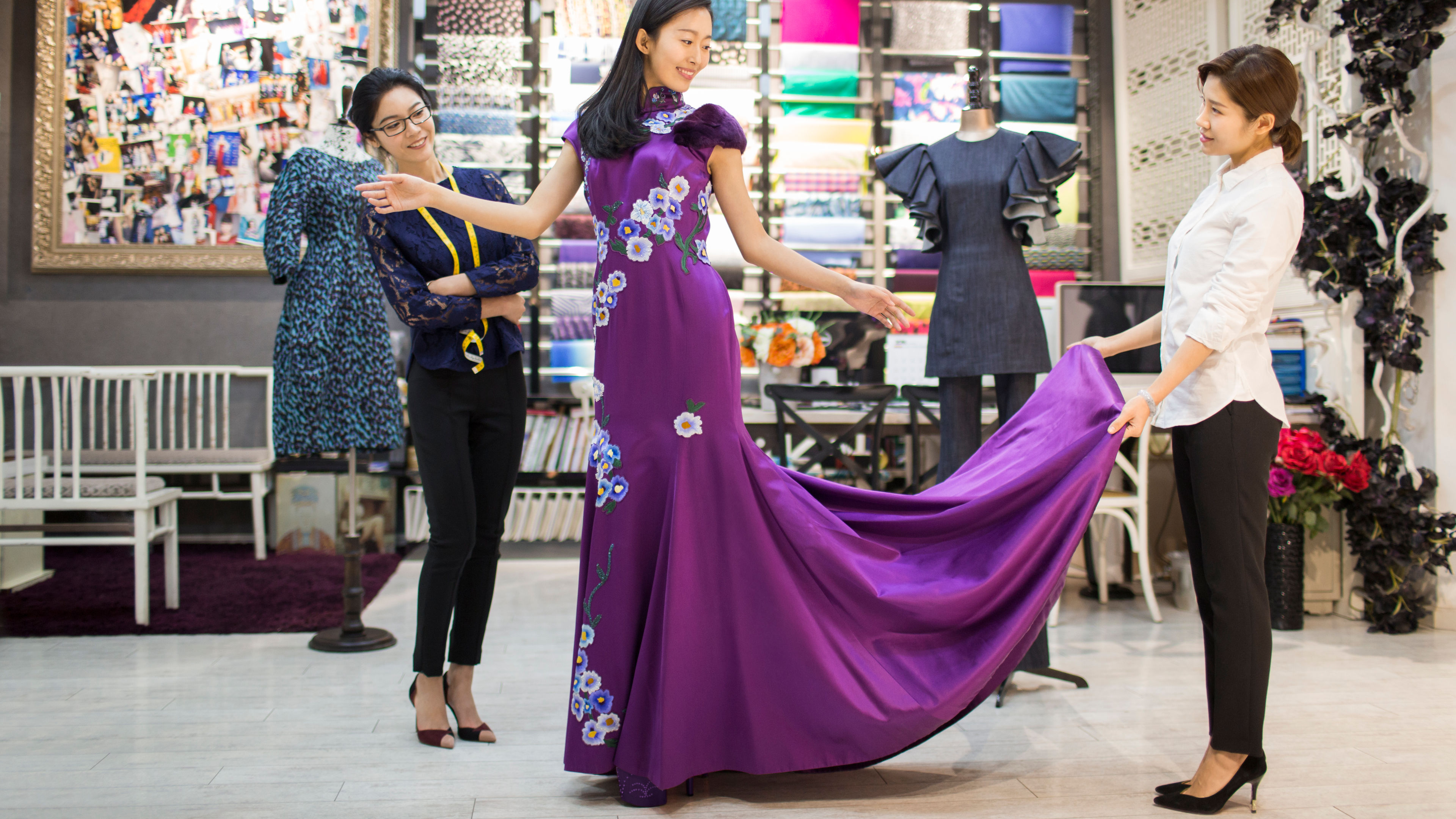 Fashion designer examining dress on customer 