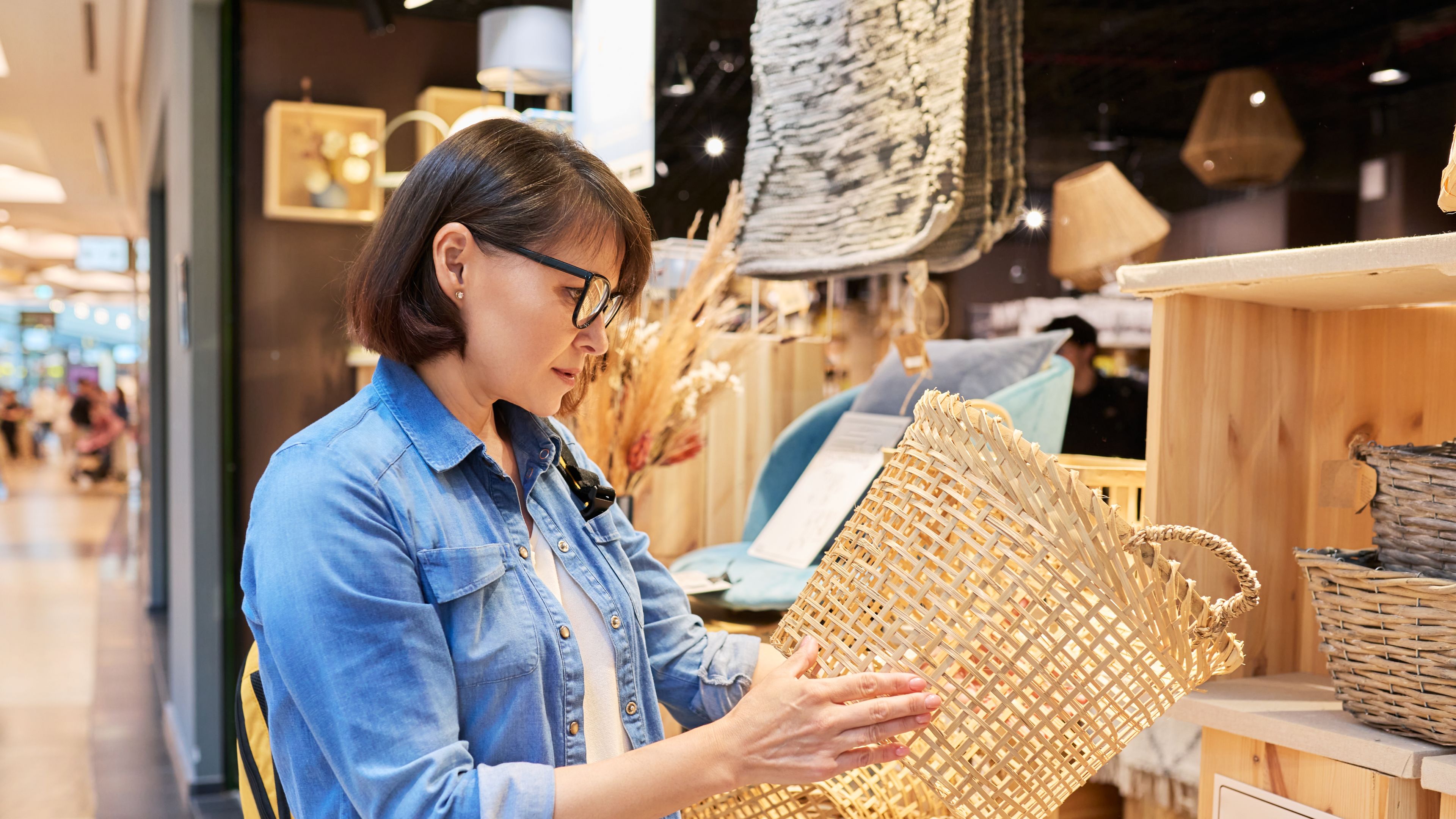 Mature woman shopper pagpili ng interior wicker baskets sa home decor store 