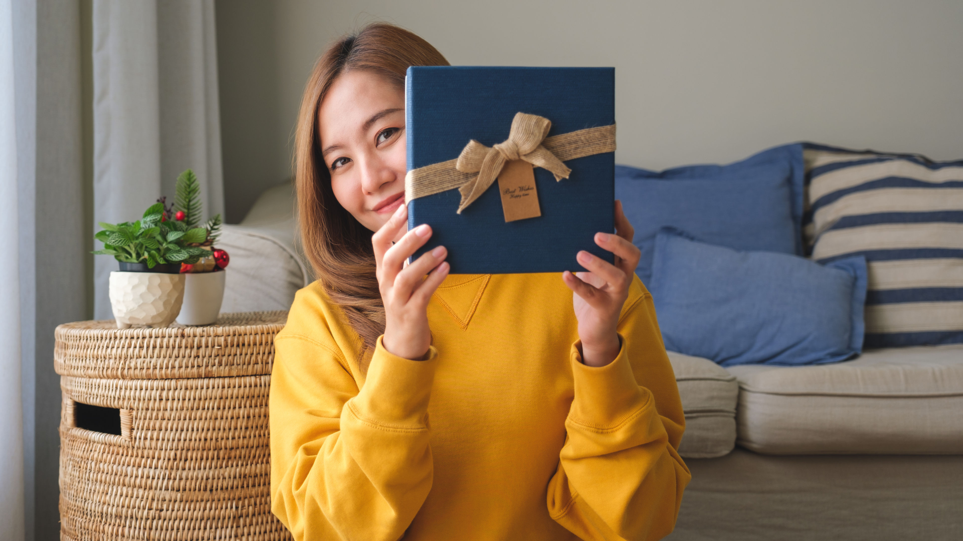 Young woman holding a present box at home.