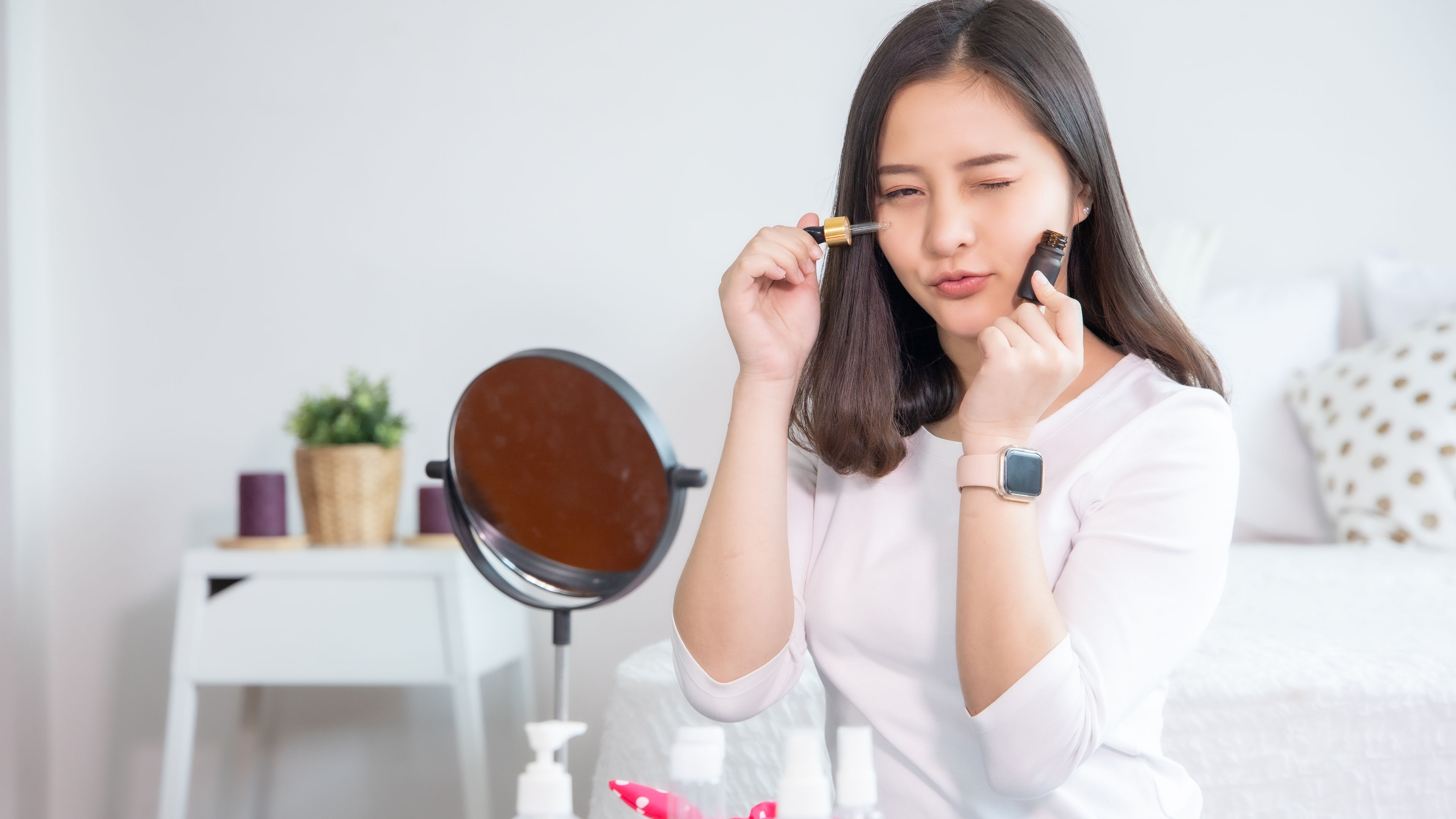 Potret wanita muda Asia menggunakan kosmetik di rumah.