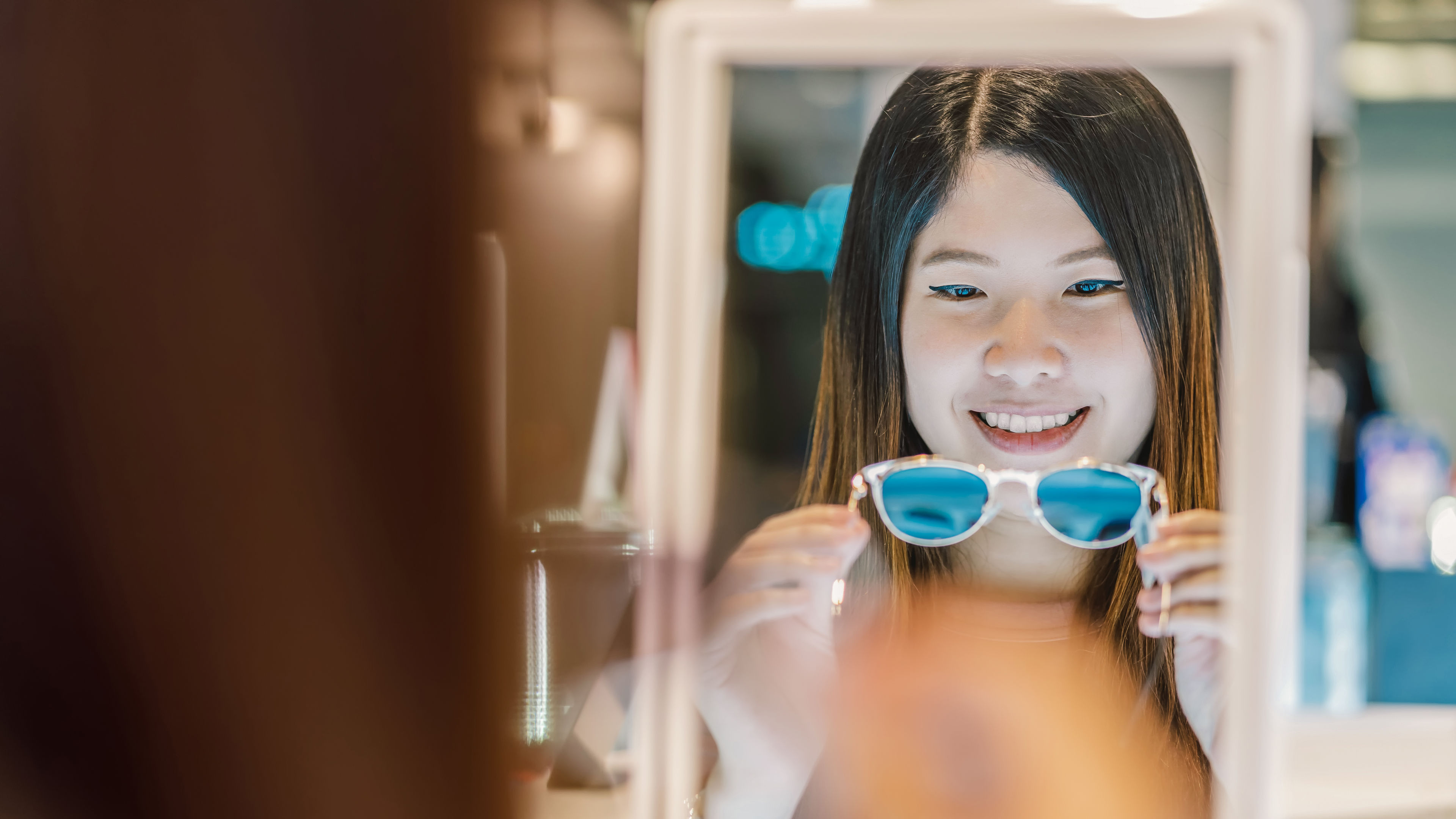 Happy Asian woman looking and choosing eyeglasses in store shop at department store. 