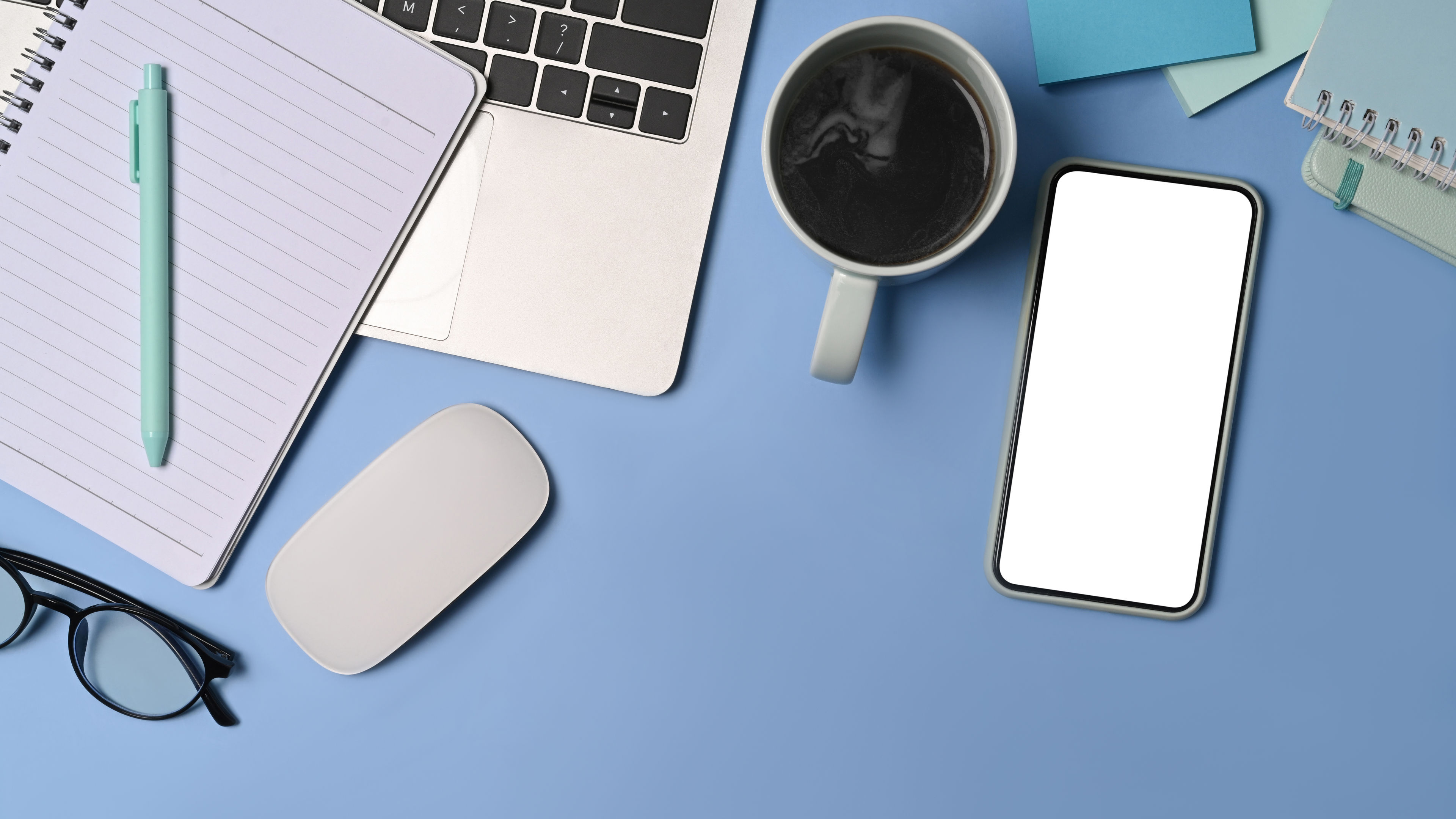 Smart phone, coffee cup and notepad on blue background. 