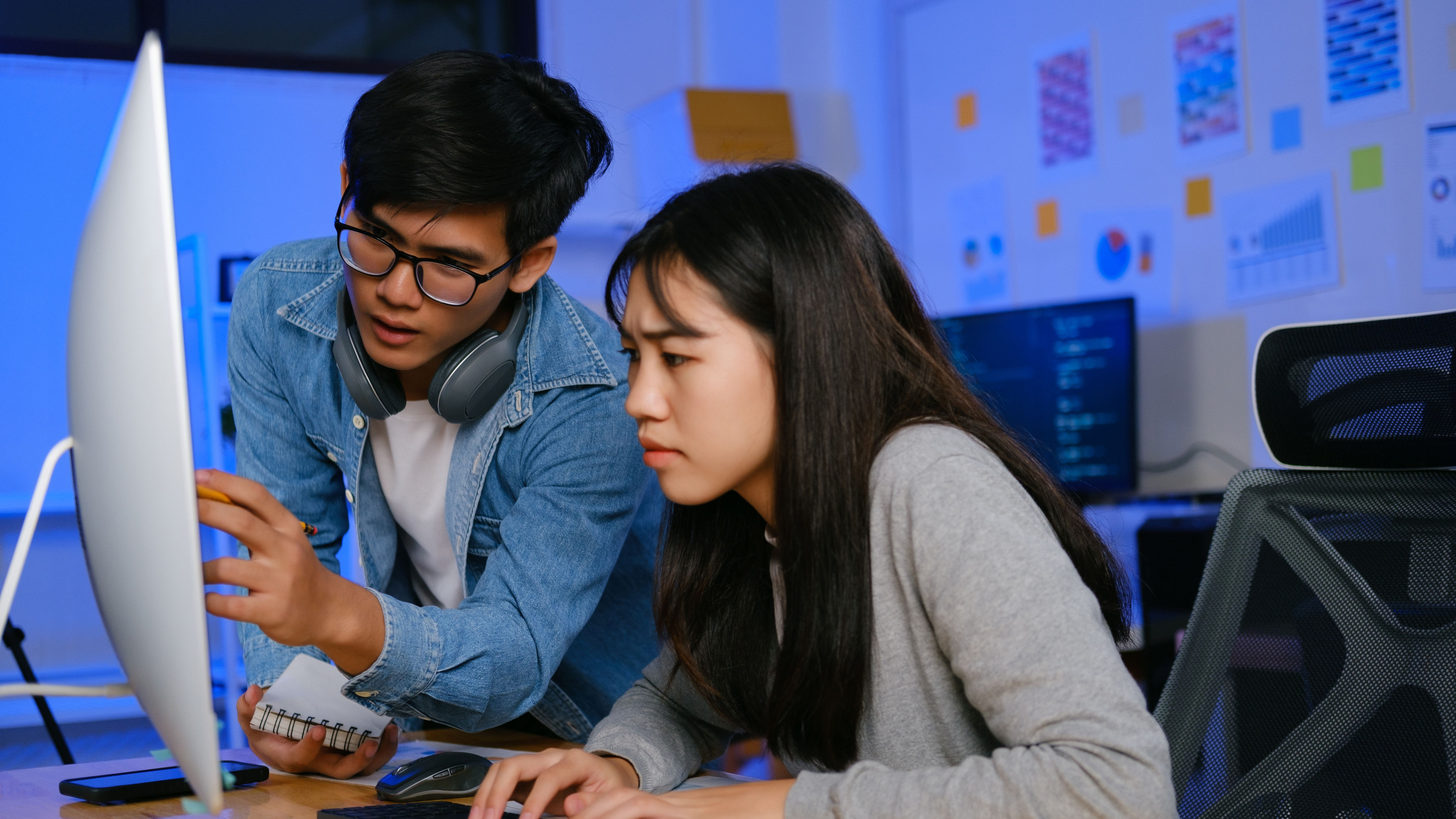 Two students concentrate on a computer, sharing ideas and working together.