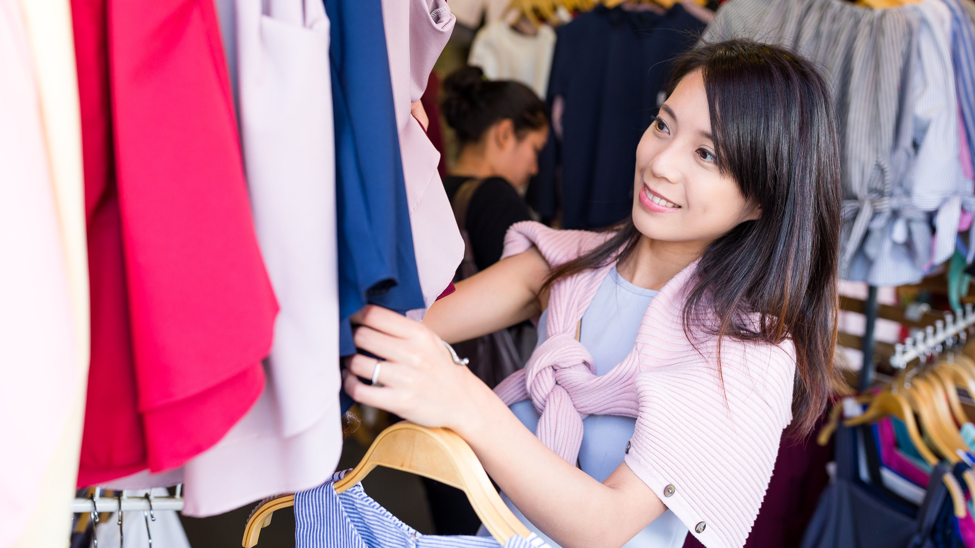 A young Asian woman in blue top and pink jacket Shopping for clothes.