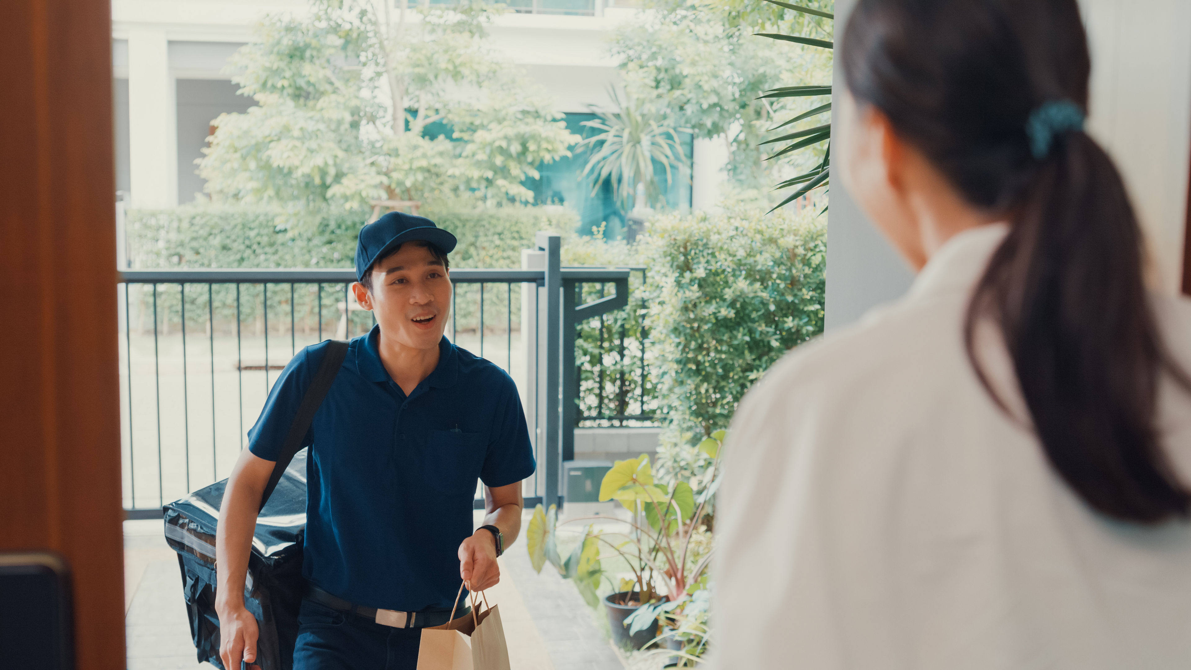 A young delivery boy giving food in paper bag 