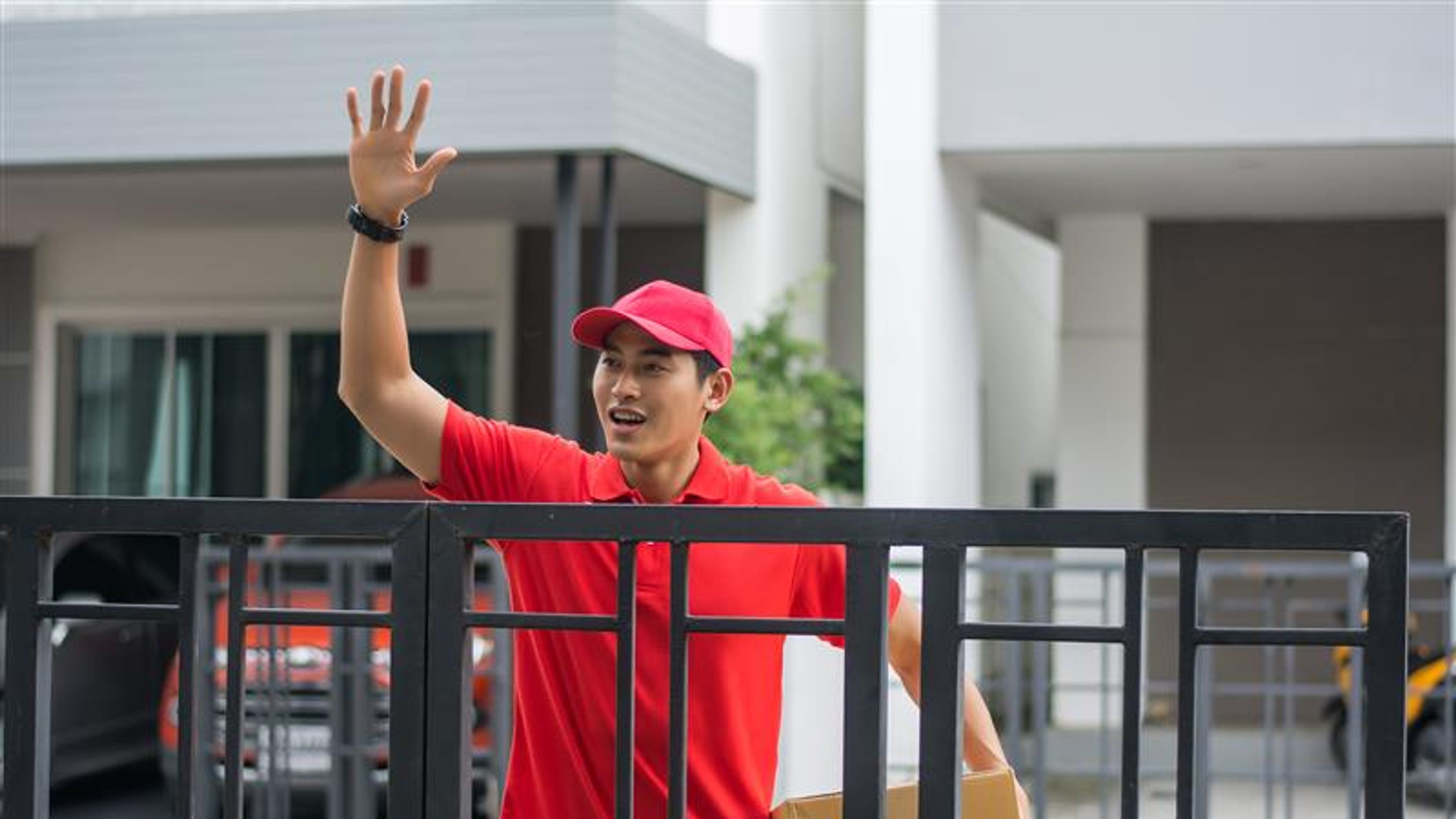 A young delivery man waving his hands 