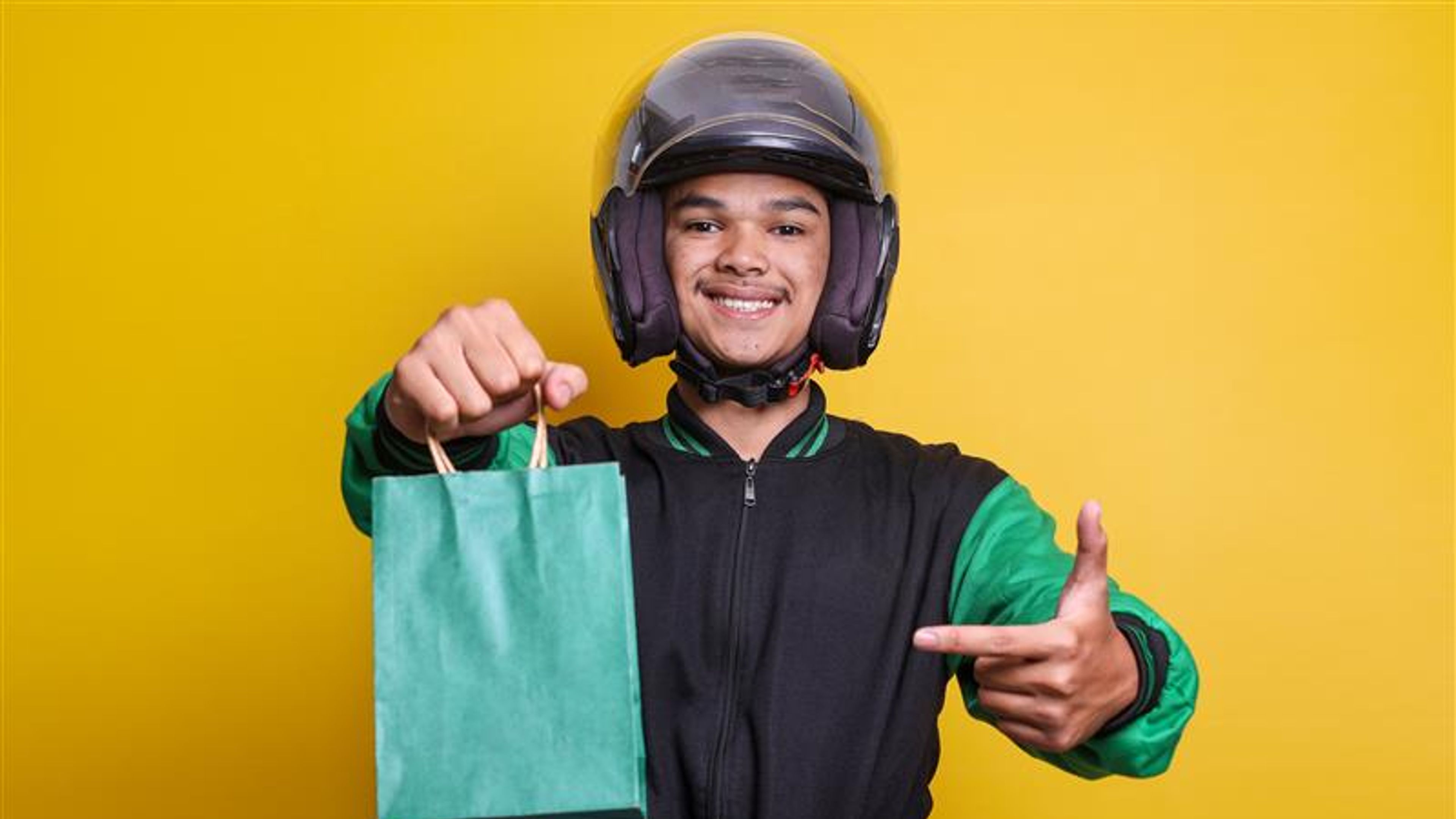 A happy delivery man with green paper bag 