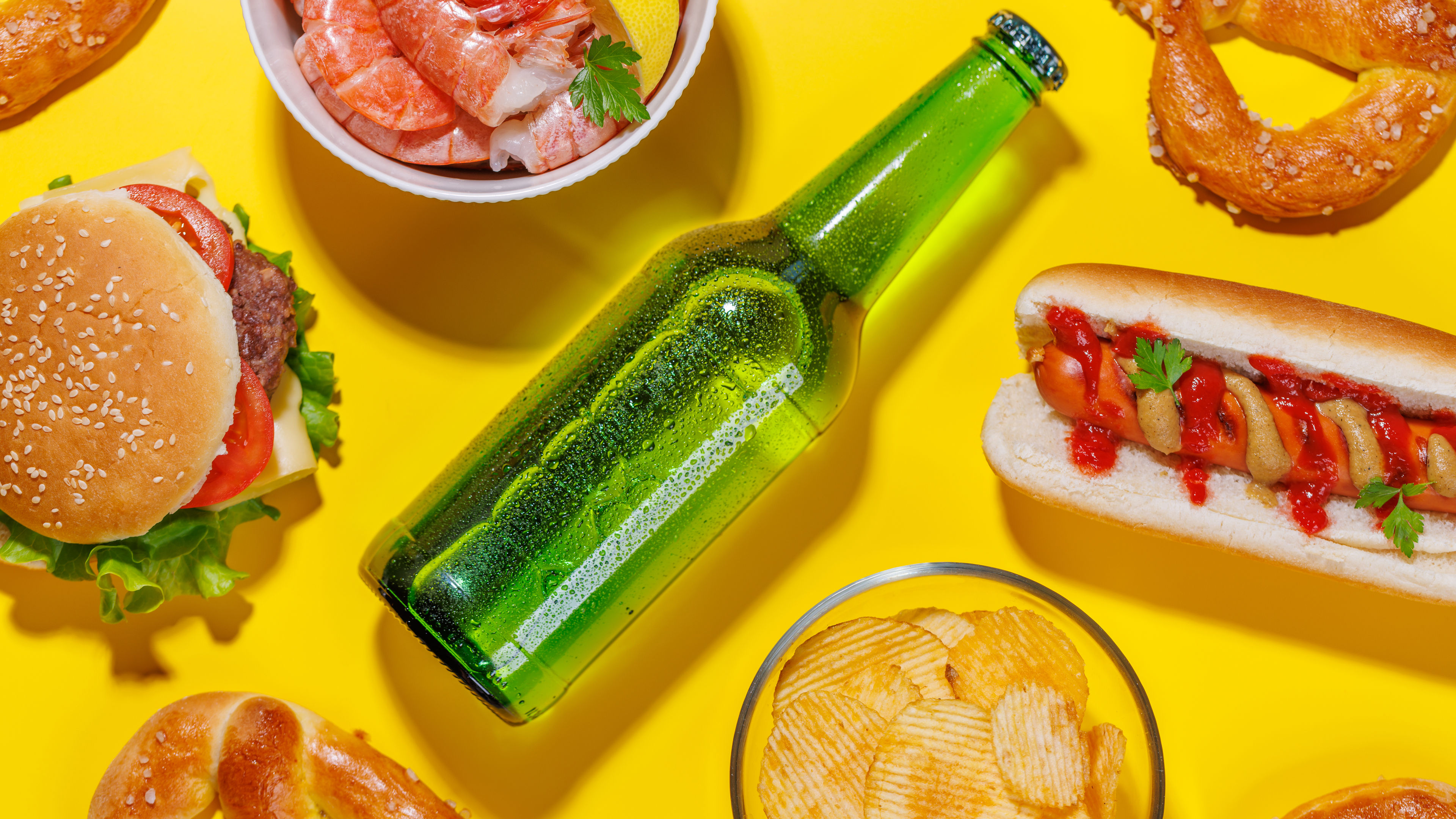 A vibrant photo showcasing a bottle of beer surrounded by various snacks and fast food 