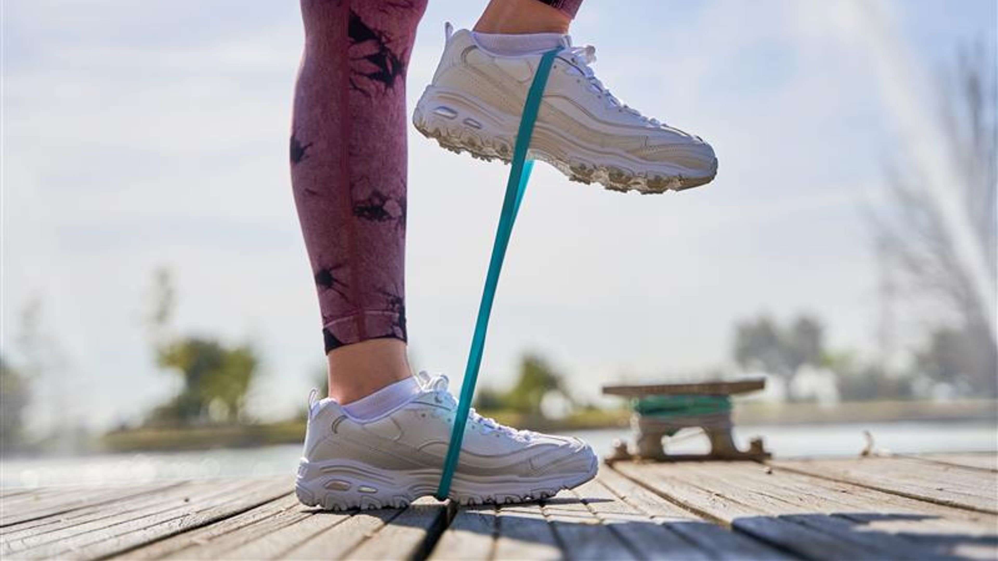 A woman is balancing on her toes while holding a resistance band. 