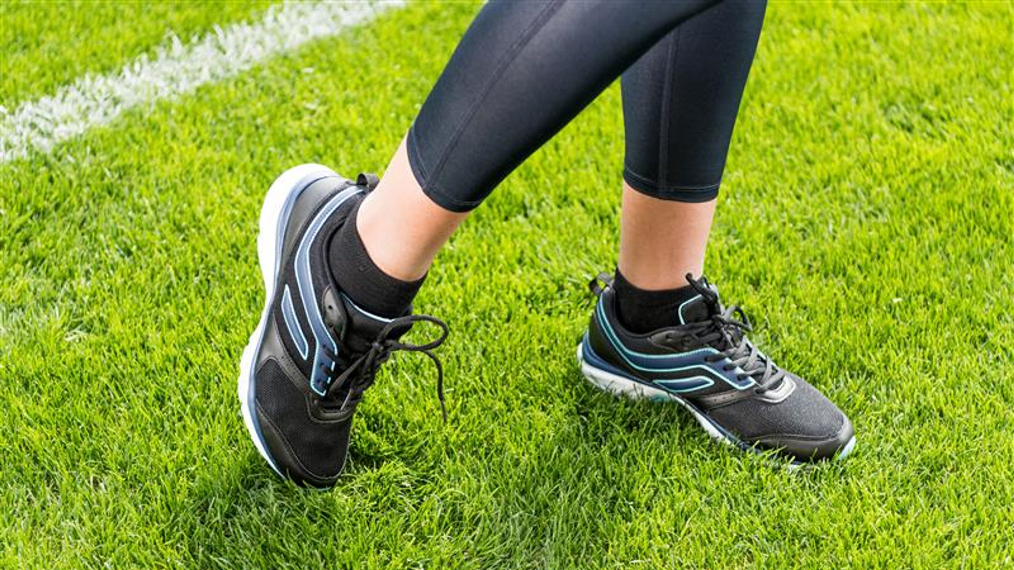 Close-up partial view of sportswoman standing on soccer stadium grass 