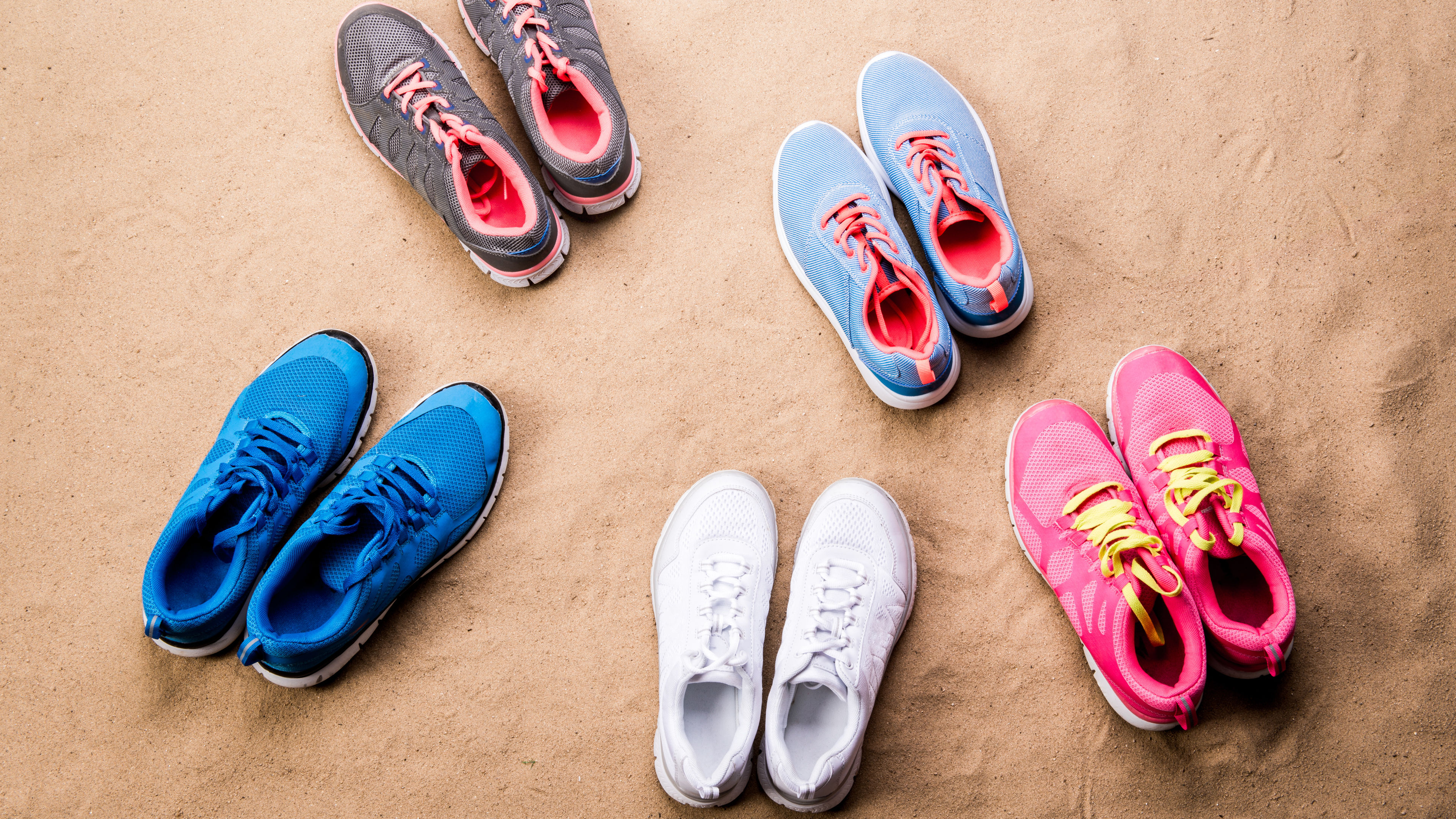 Various colorful sports shoes laid on sand beach 
