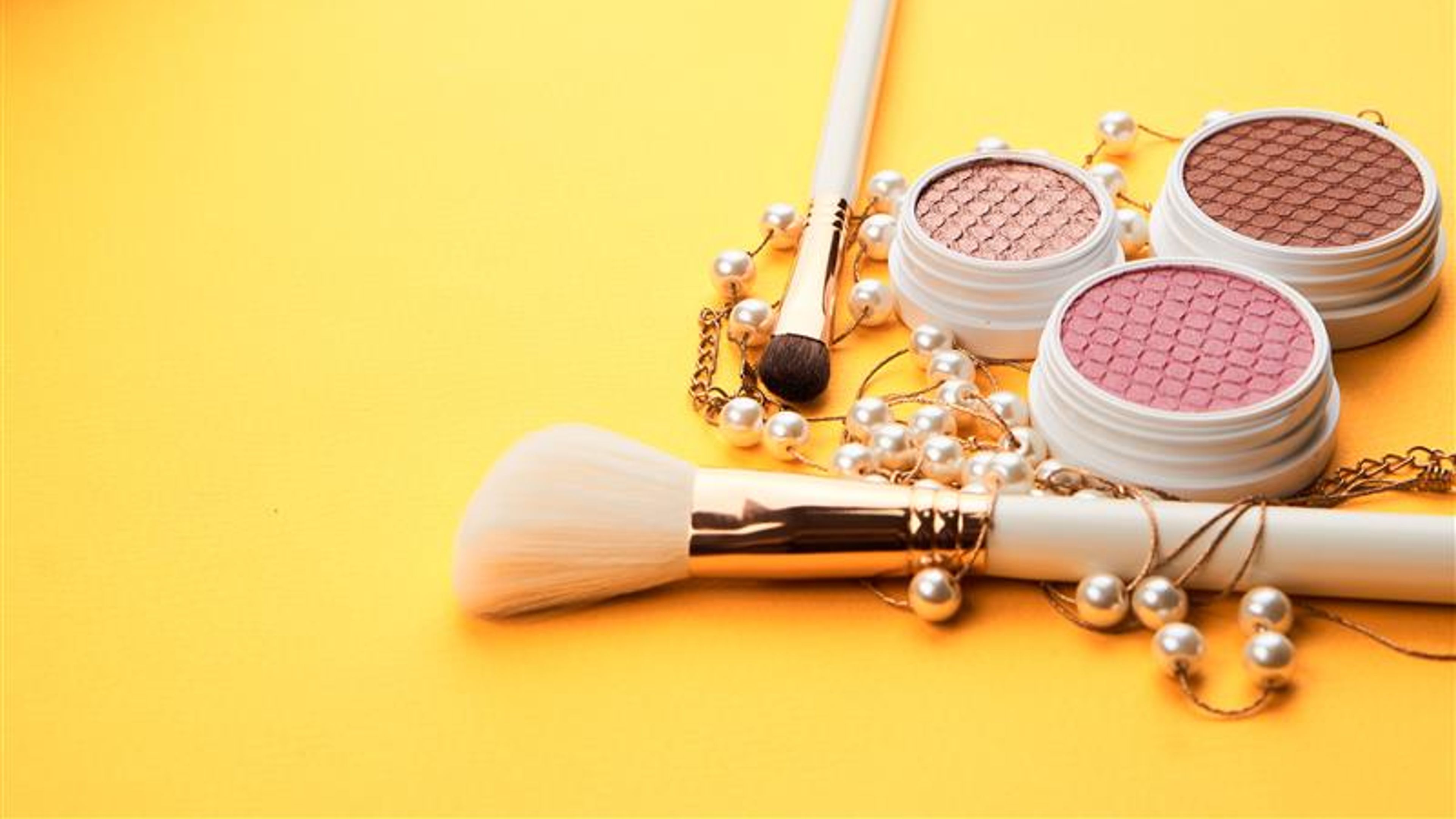 Eyeshadows on a yellow background professional cosmetics makeup brushes soft sponge fashion glasses. 