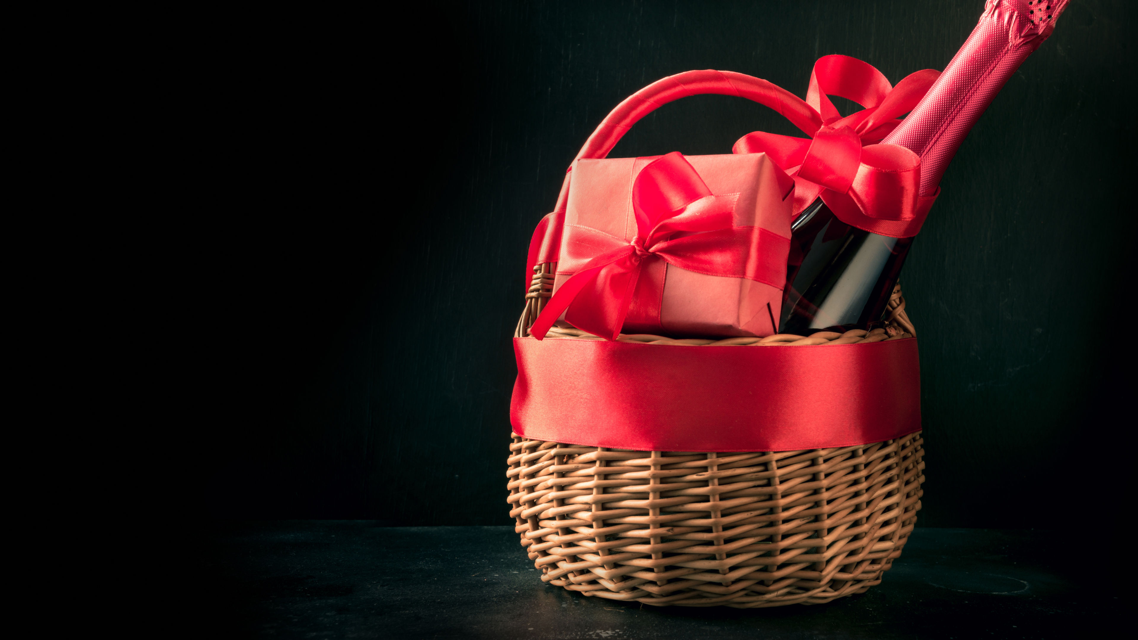 Gift hamper, red gift, bottle of champagne on black. Isolated. Romantic present. 