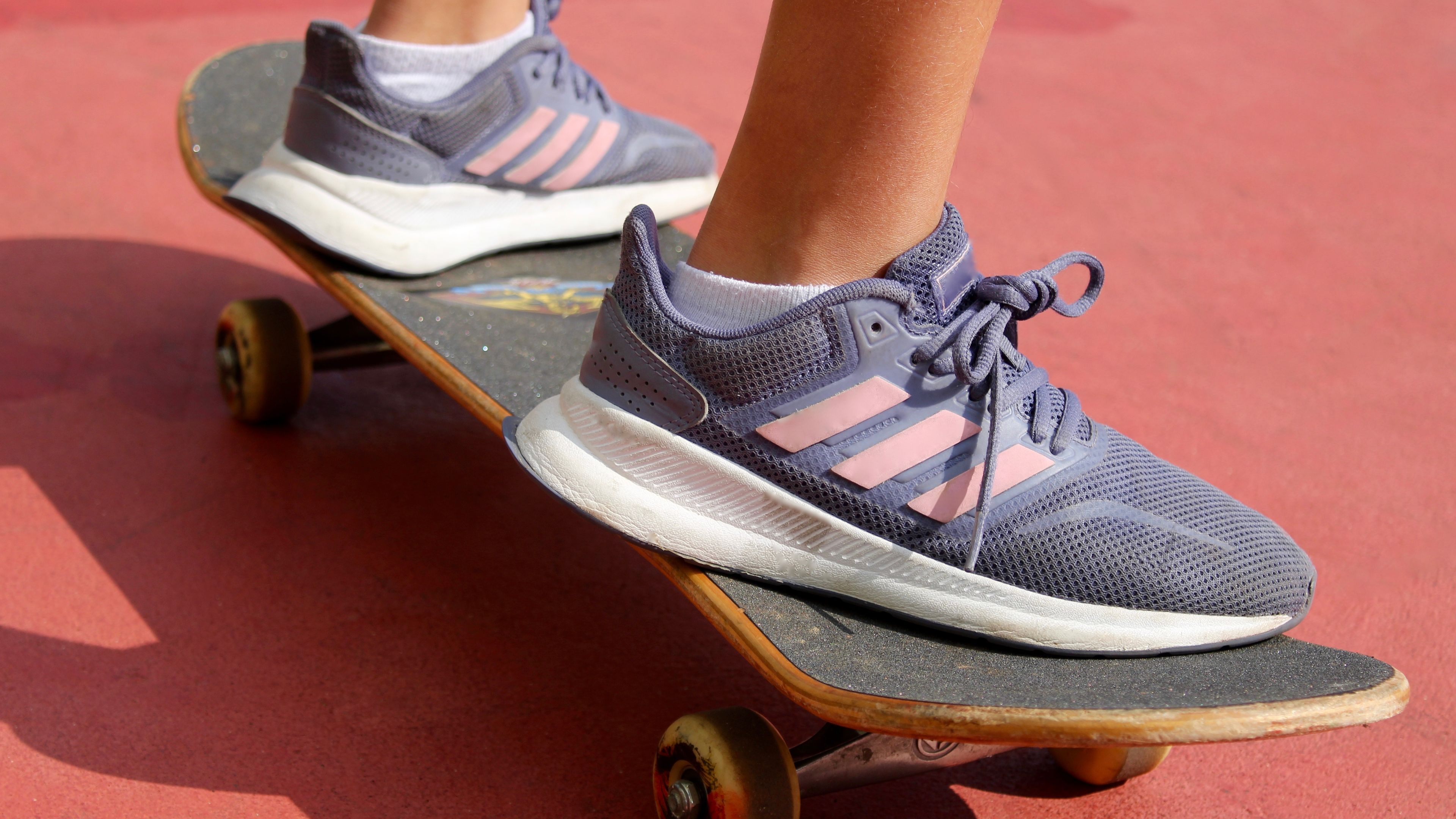 A young woman gracefully glides on her skateboard, balancing with ease and confidence as she carves through the streets. 