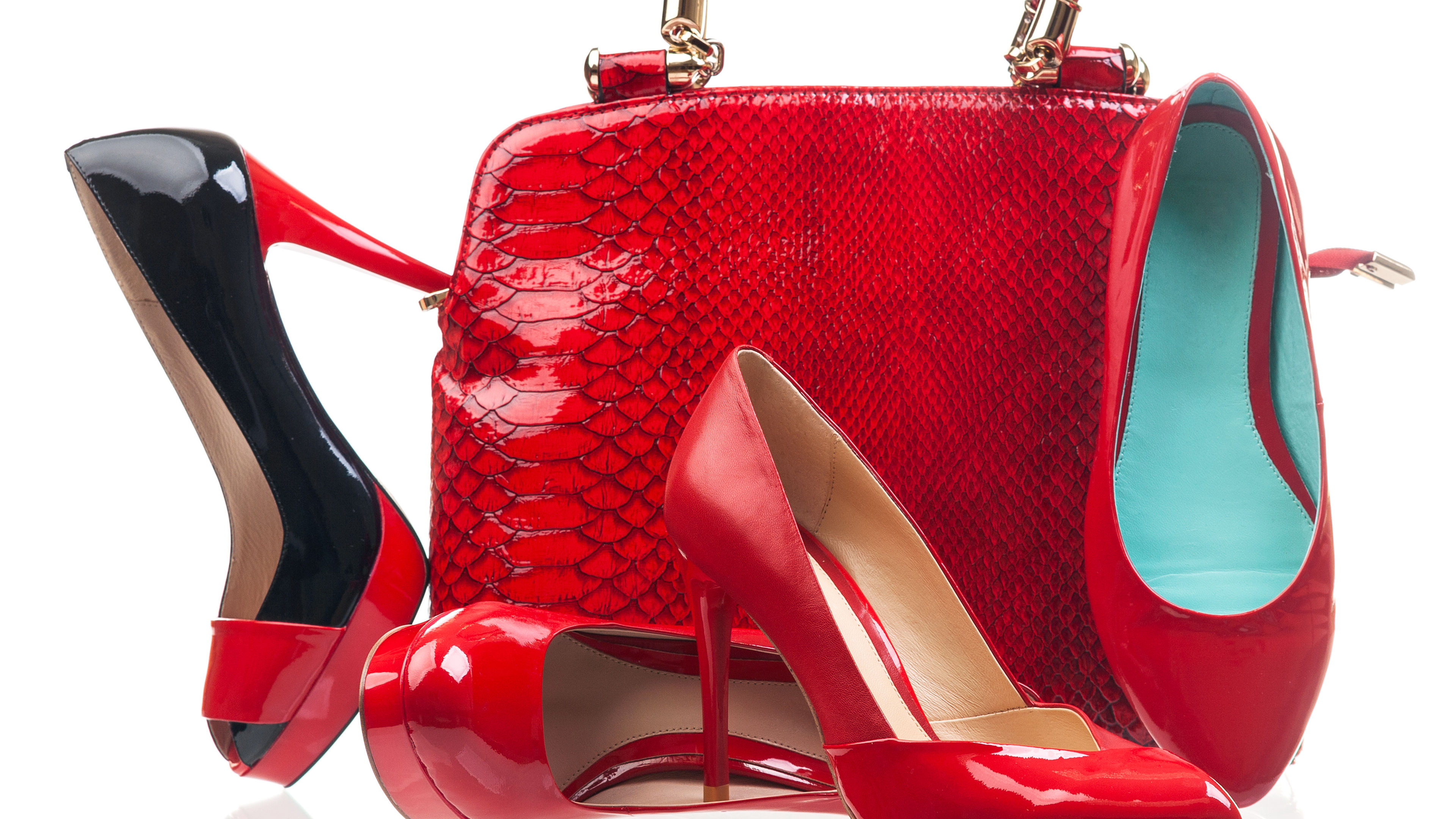 A stunning pair of red fashion women's shoes is elegantly displayed alongside a matching handbag against a crisp white background.