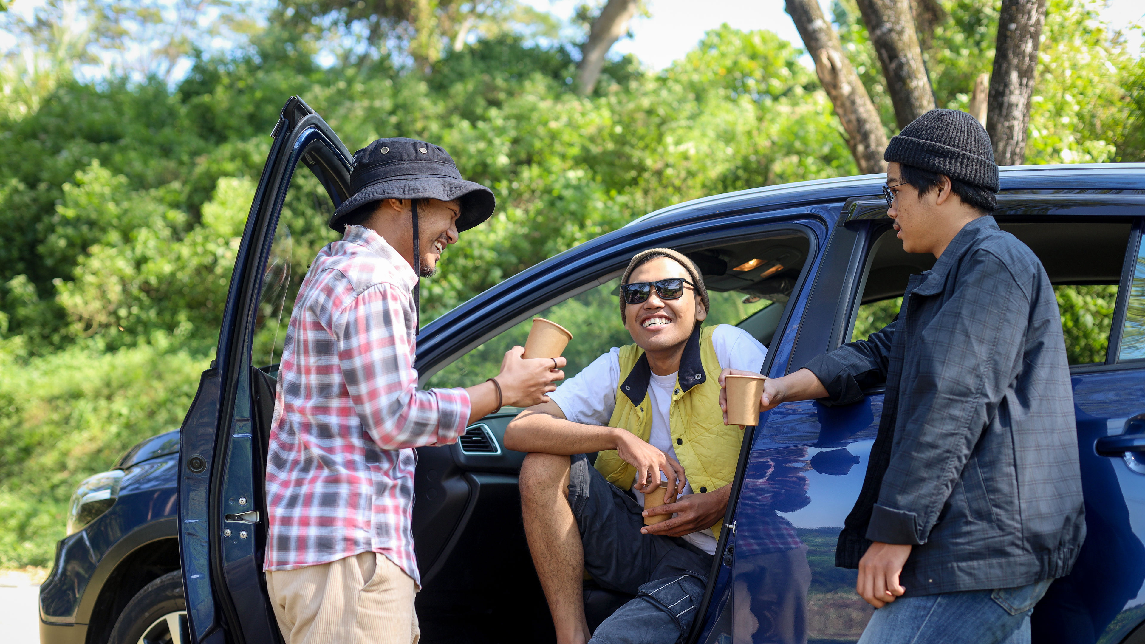 Three male friends on a road trip having their leisure time drinking coffee 