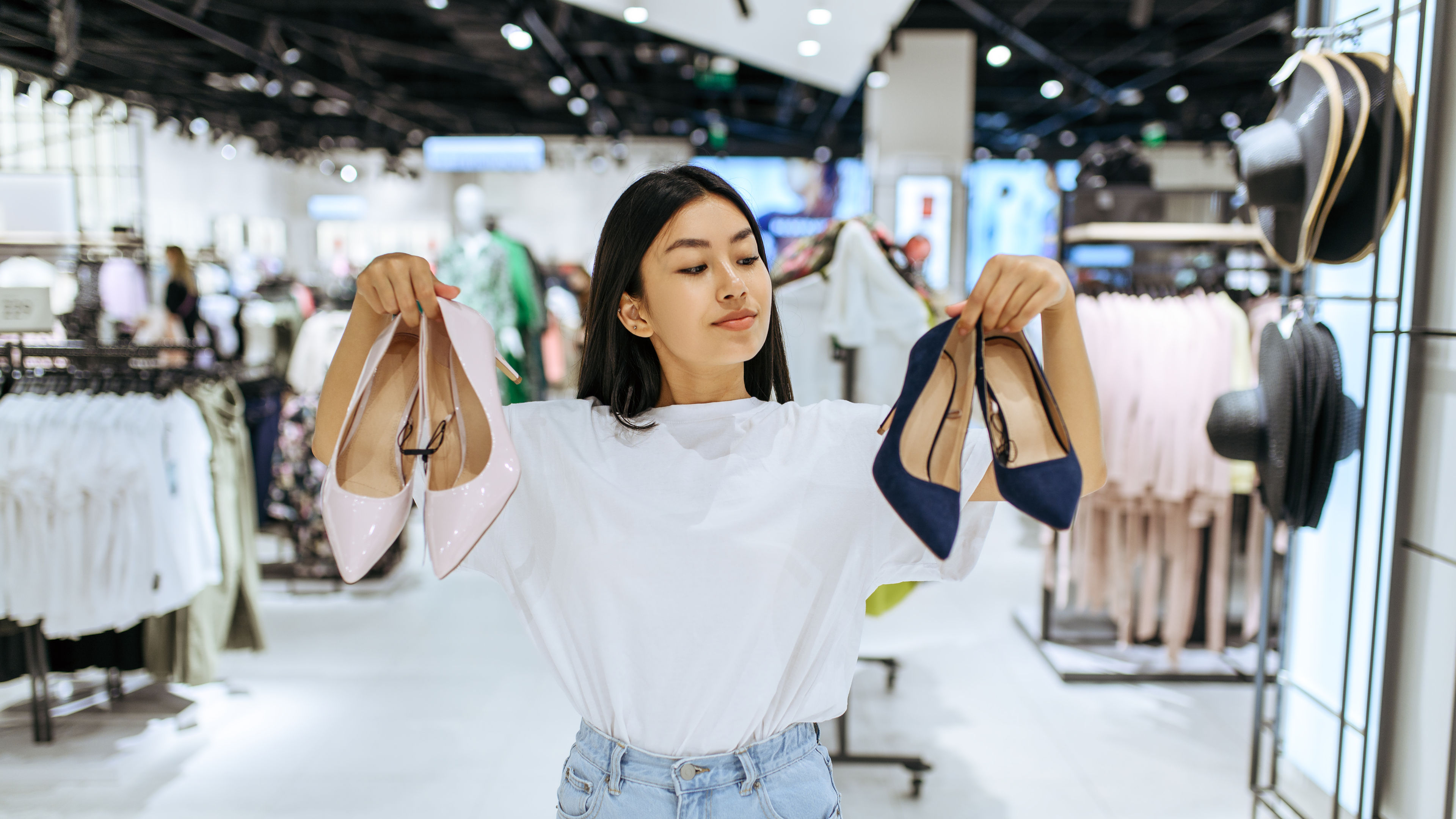 Cute woman choosing shoes in clothing store 