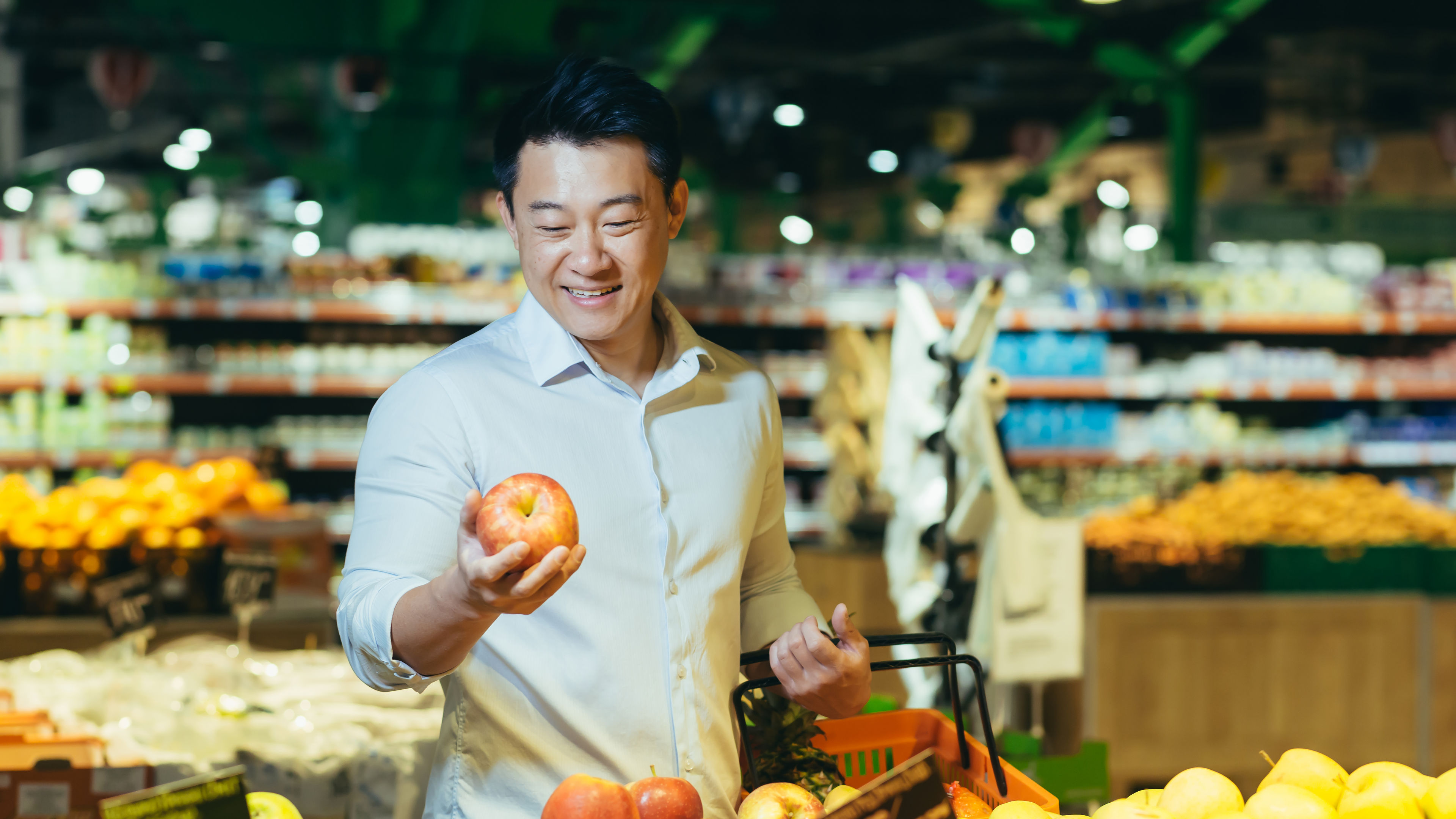 Customer standing a grocery store and picks apple 