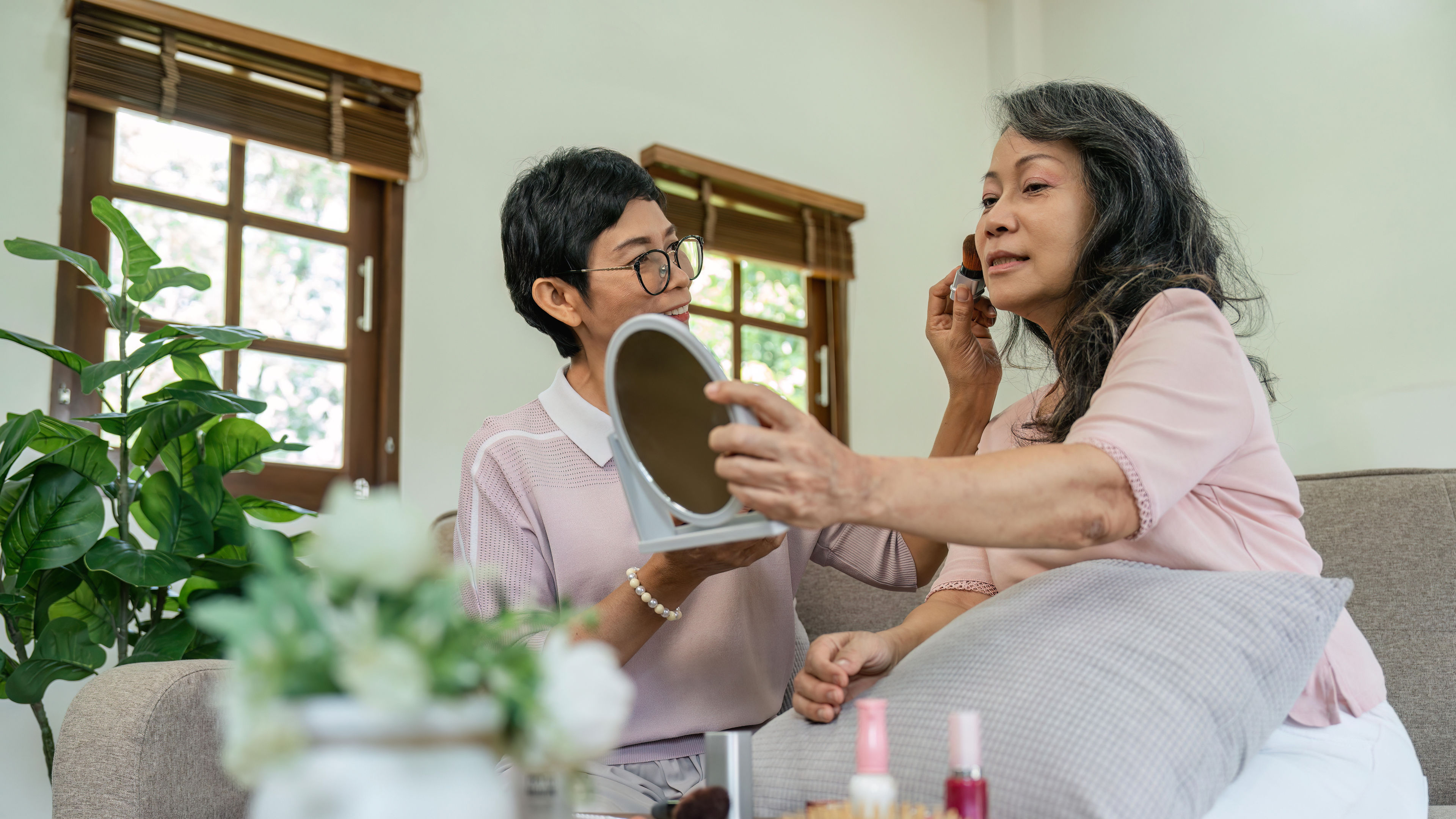 An intimate and stylish portrayal of two women engrossed in their makeup routine, each showcasing their unique style and flair. 