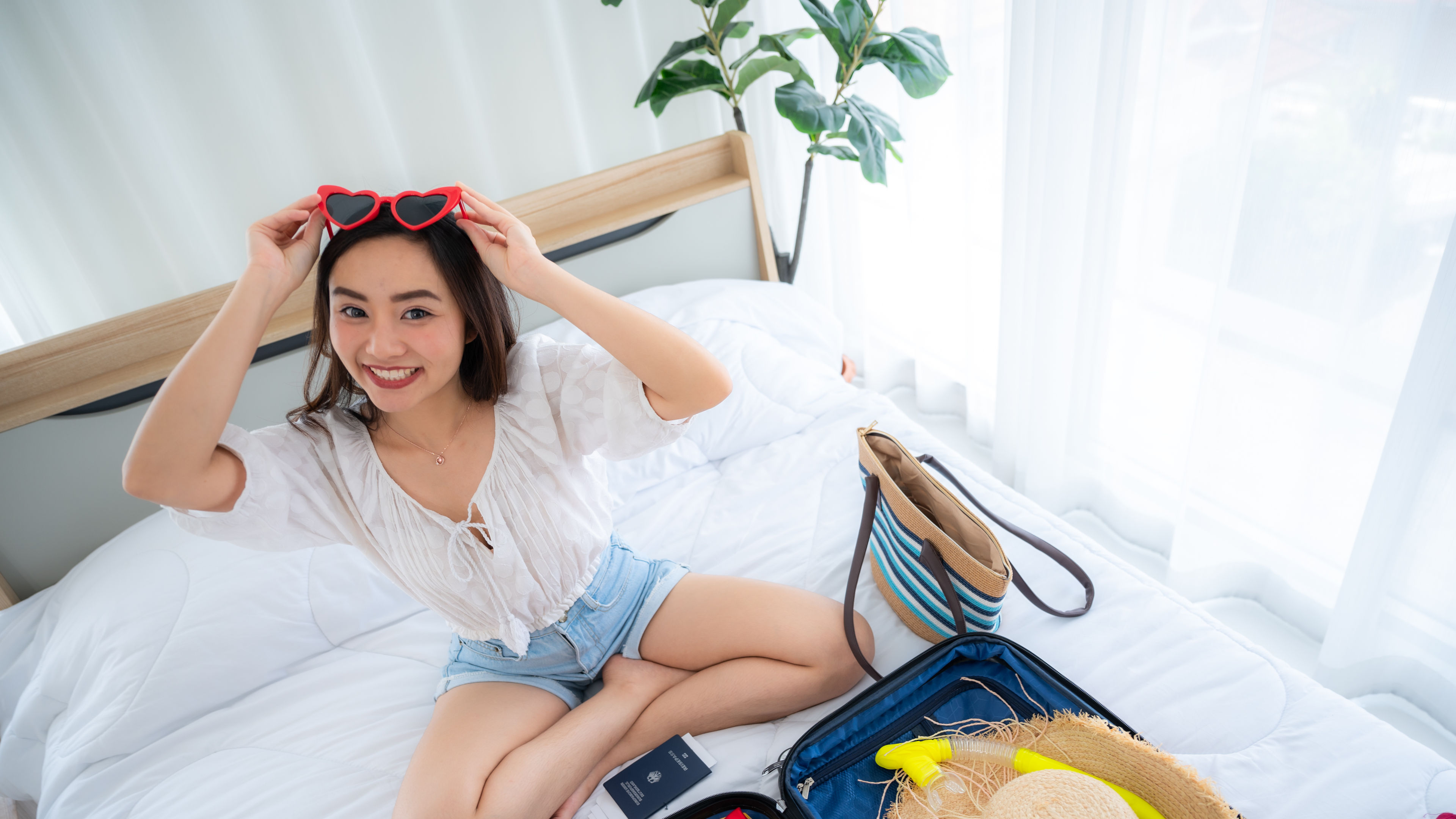 Asian women sitting on bed with suitcase