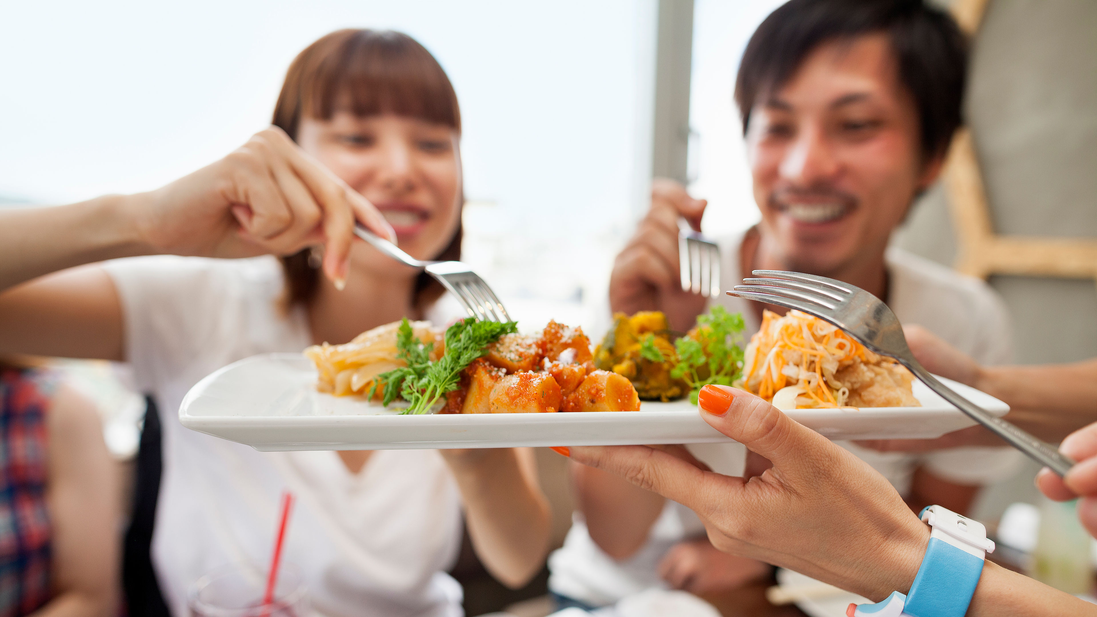 Asian friends enjoying meal around a dining table.