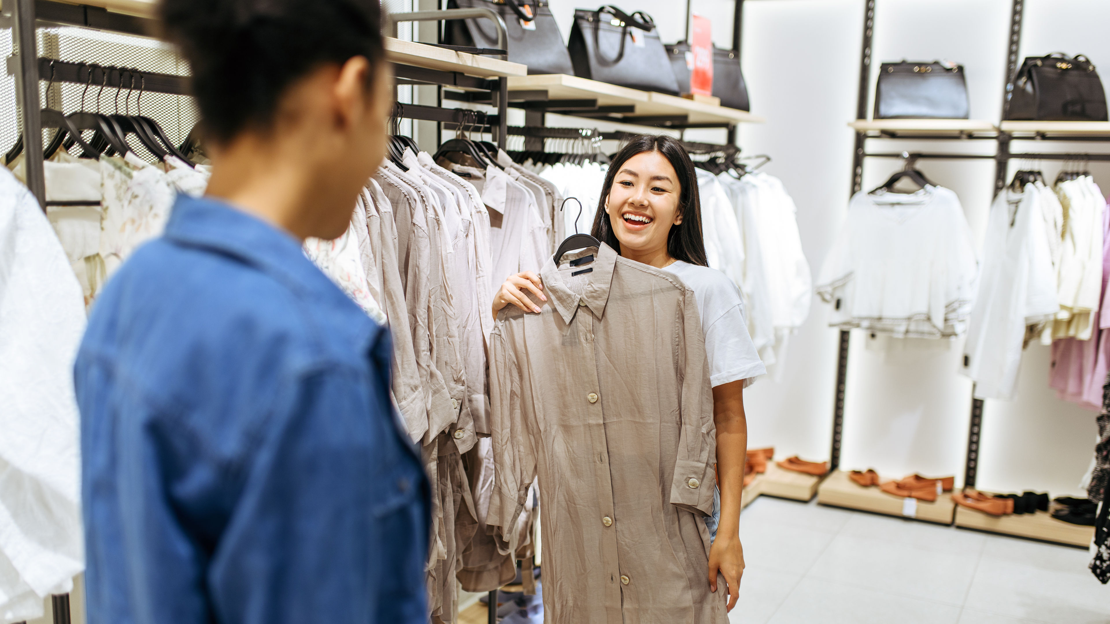 Two happy girls choosing clothes in clothing store