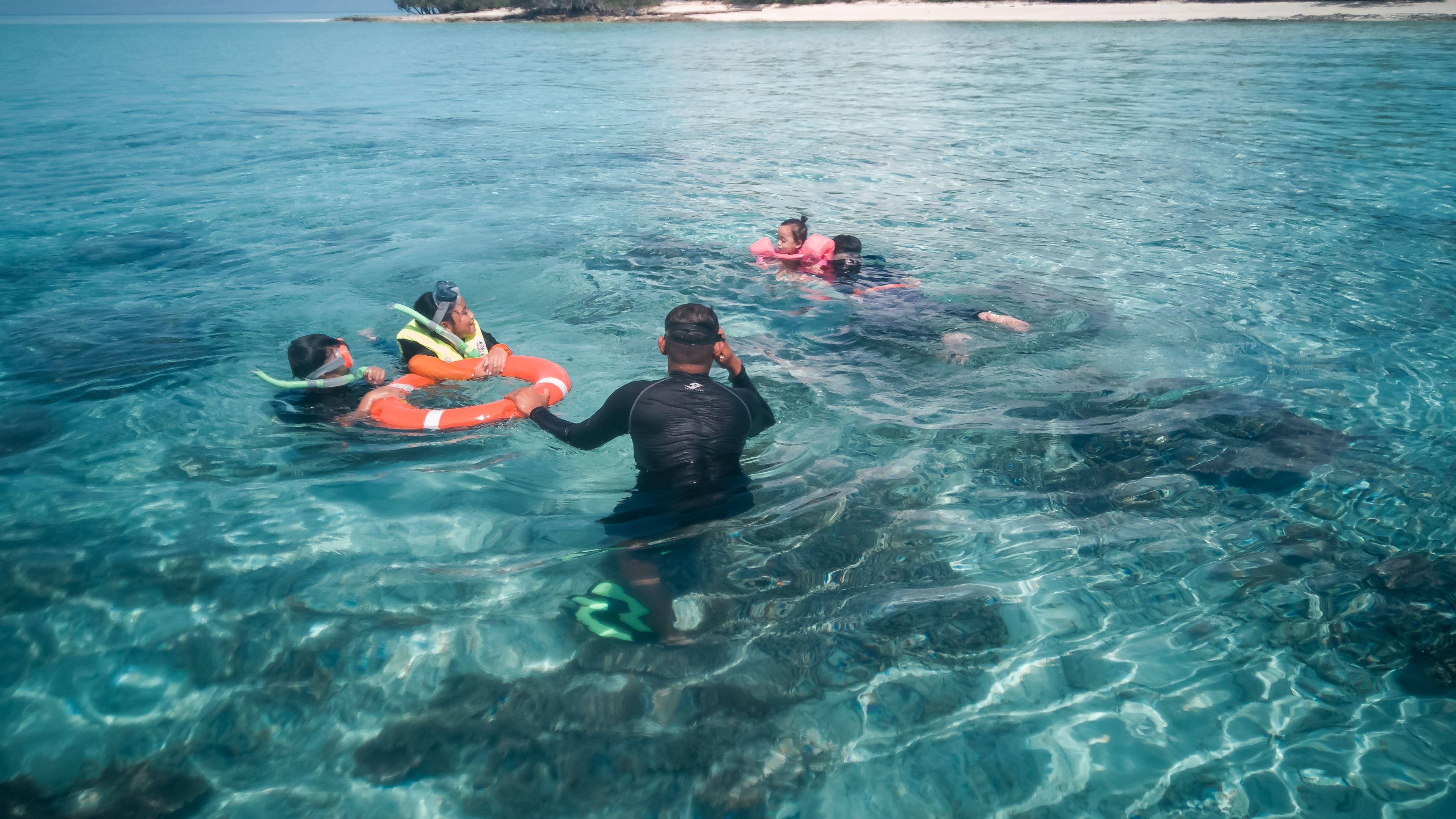 A group of tourists snorkels in clear waters