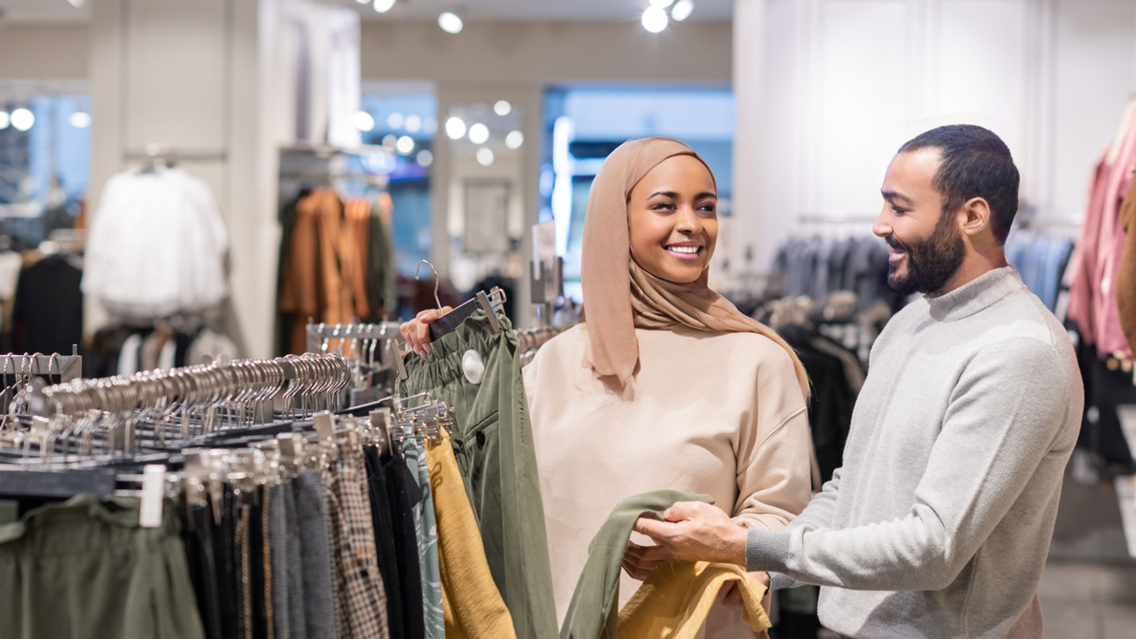 Pretty girl and young man choosing between yellow and grey pants