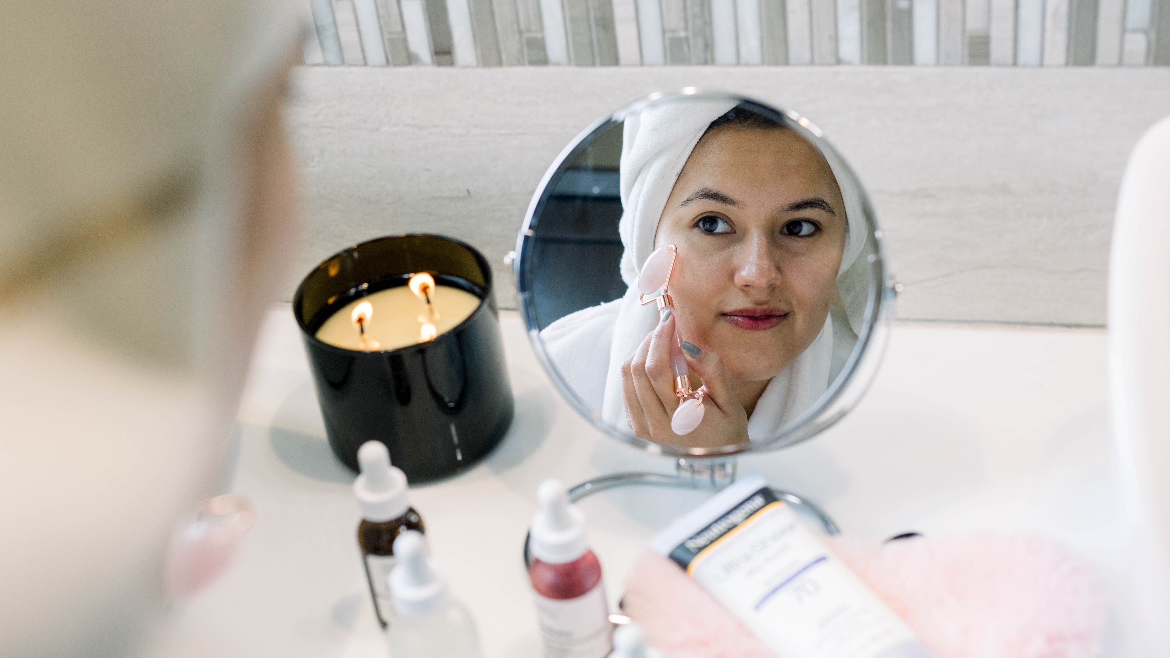 A woman gently using a rose quartz roller on her skin, enhancing her skincare routine.