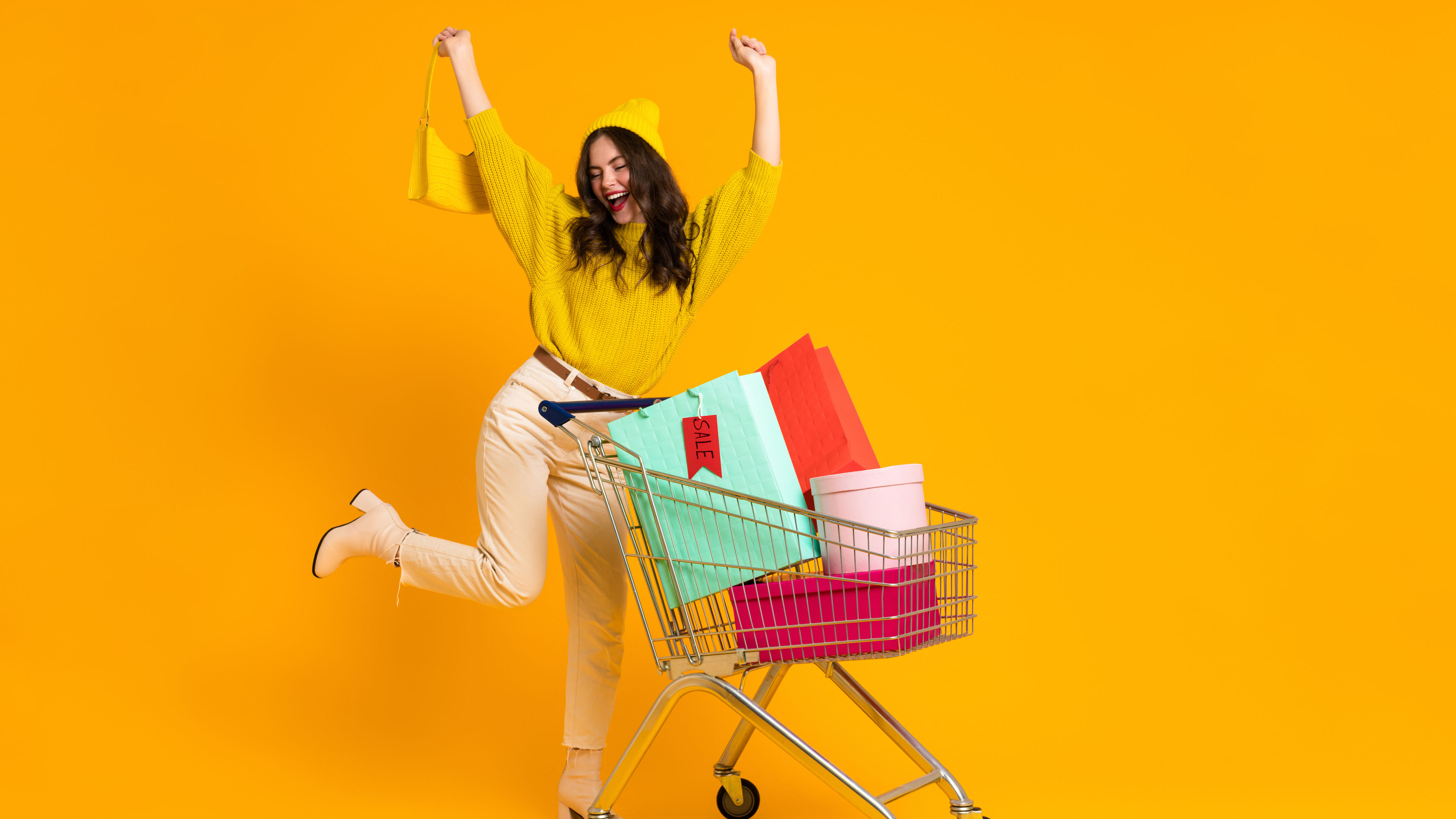 امرأة بيضاء تقوم بإيماءة الفائز أثناء الوقوف مع عربة التسوق