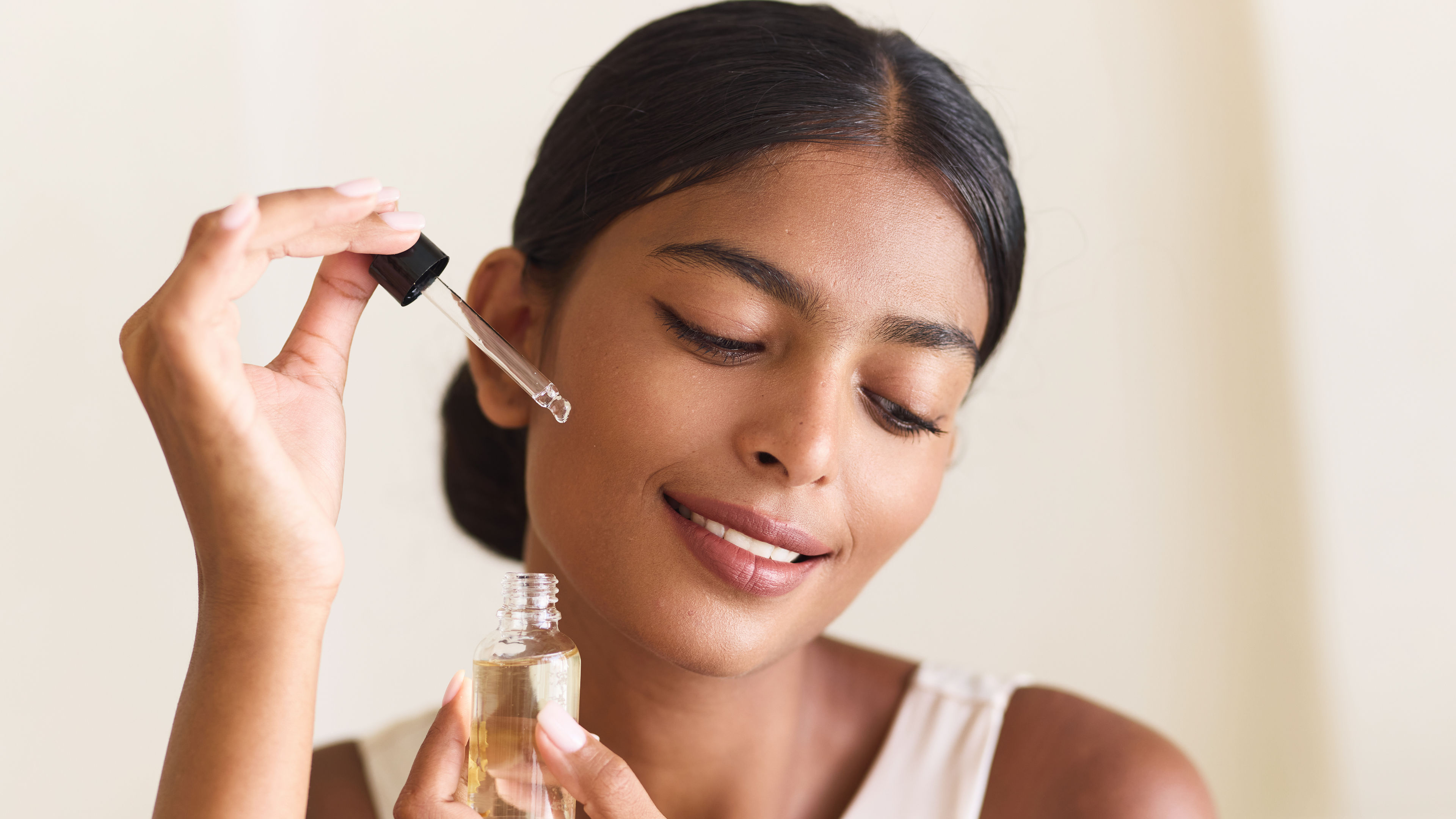 Woman applying facial oil for skincare routine and glowing skin.