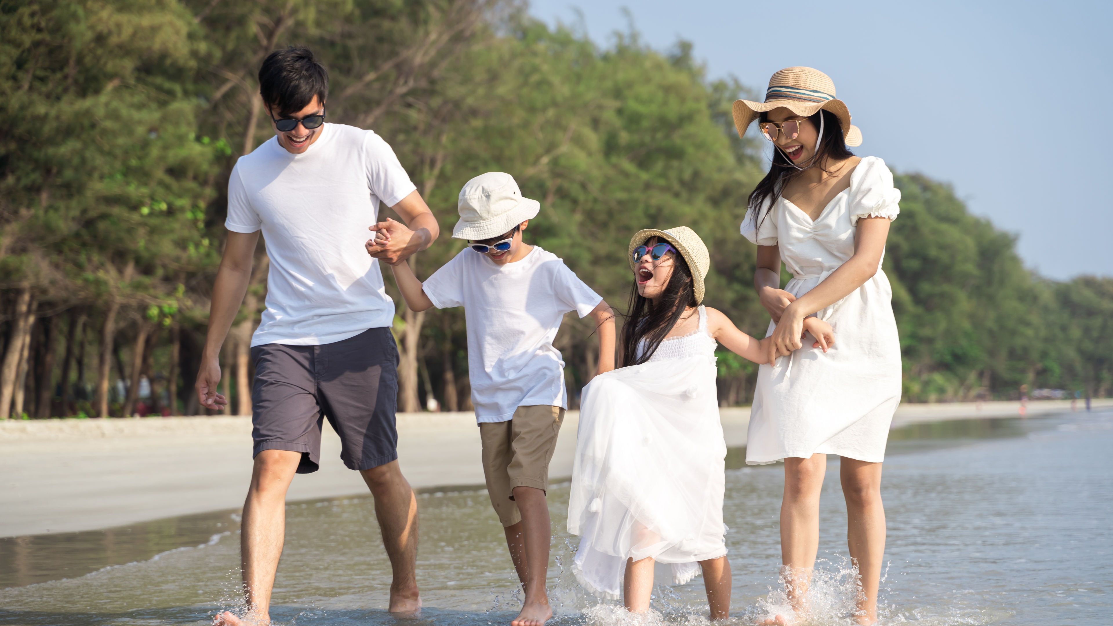 A Happy family in white walking at a beach.