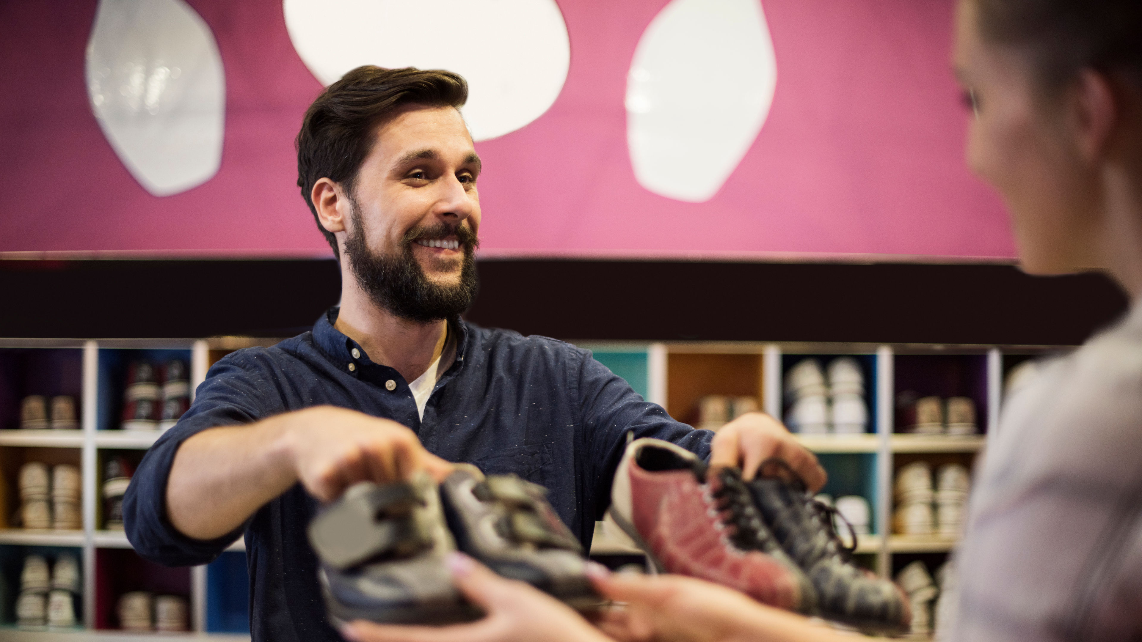 A shoe store staff handing over shoes to a customer.