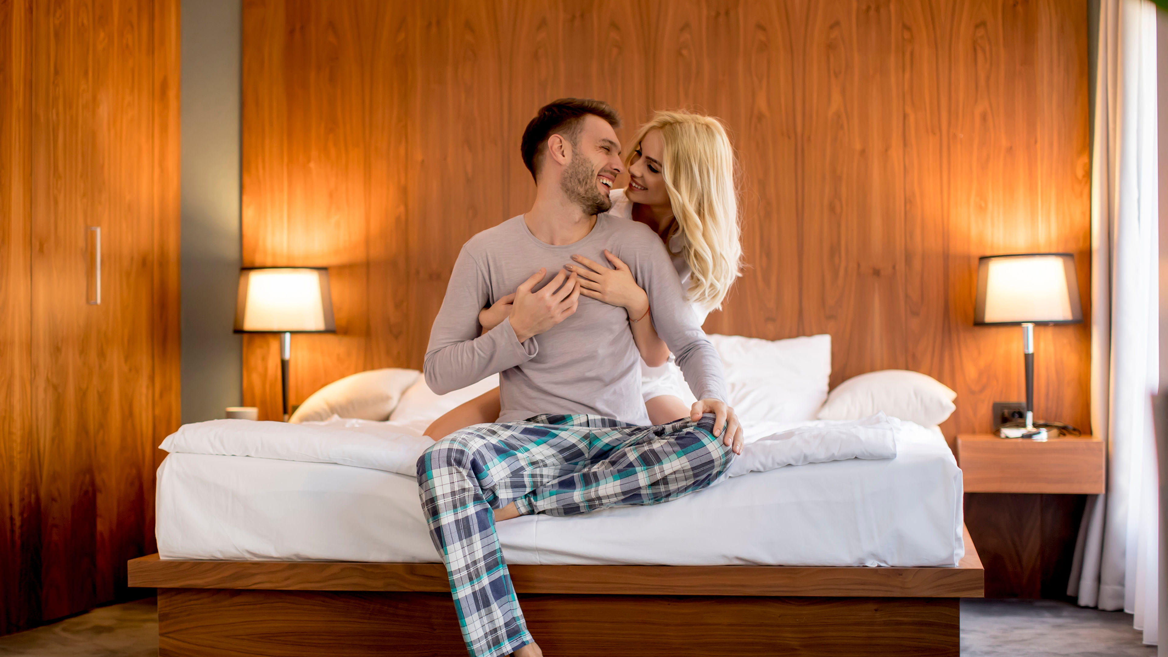 A lovely couple embracing each other in a brightly lit hotel room.