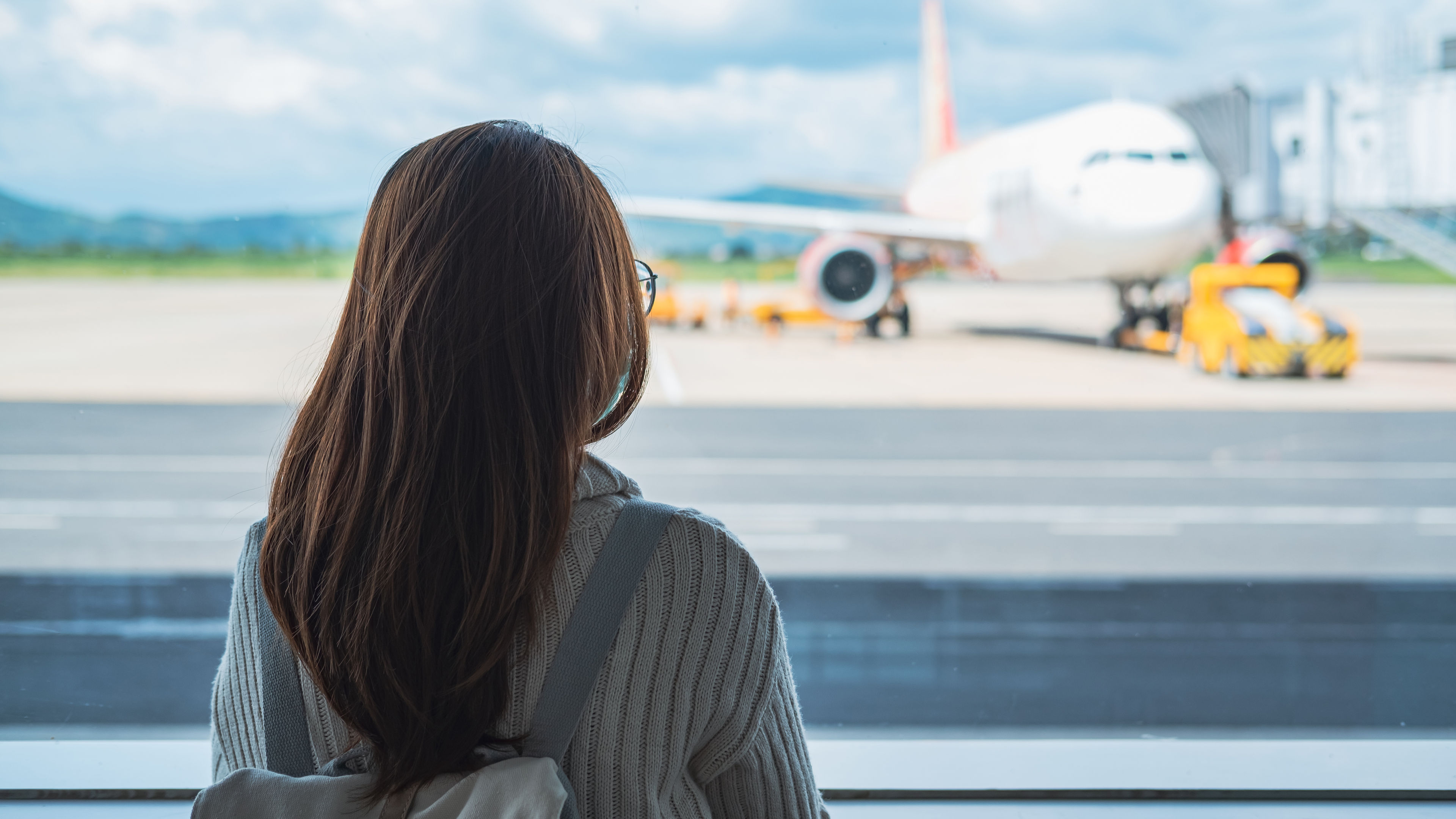 Woman watching flight from the window of an Airport.