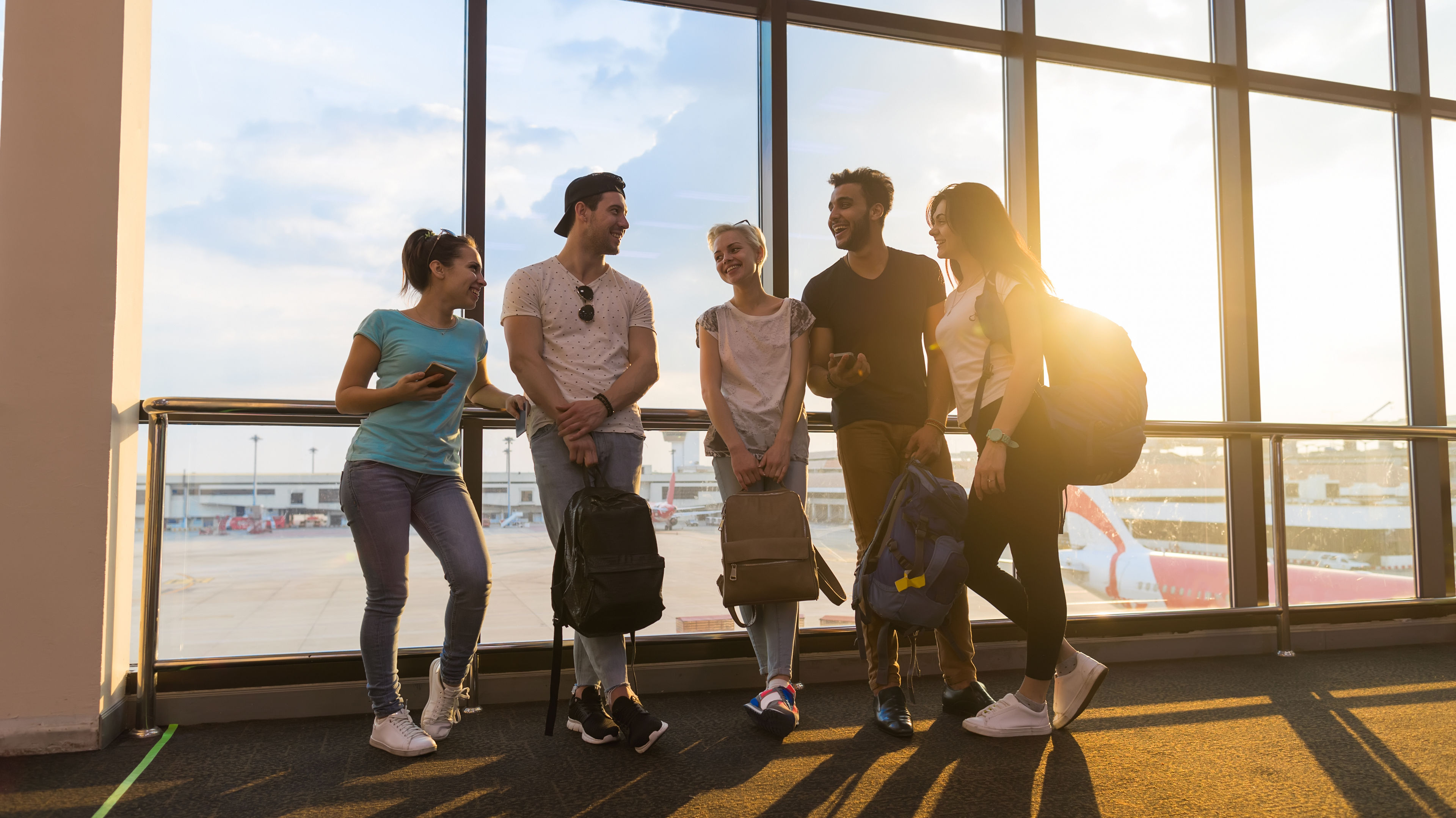 Young people group in airport lounge near windows