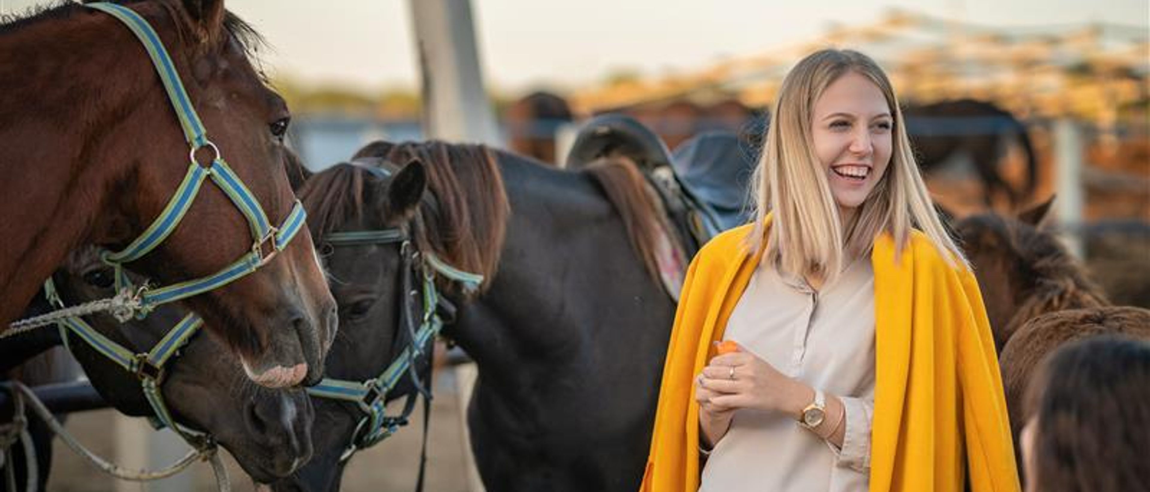 A woman with horses behind.