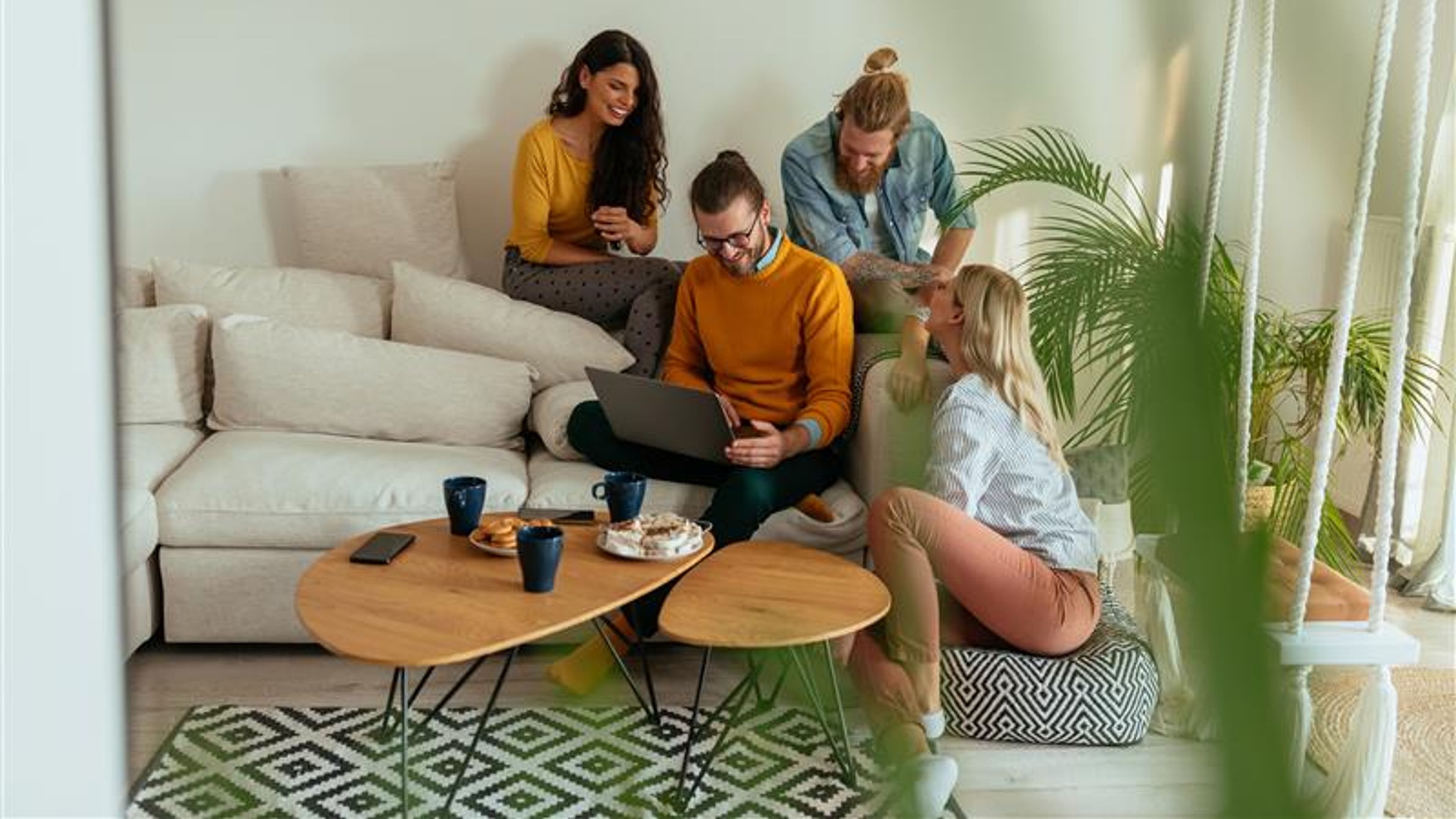Some people in a living room working on a laptop 
