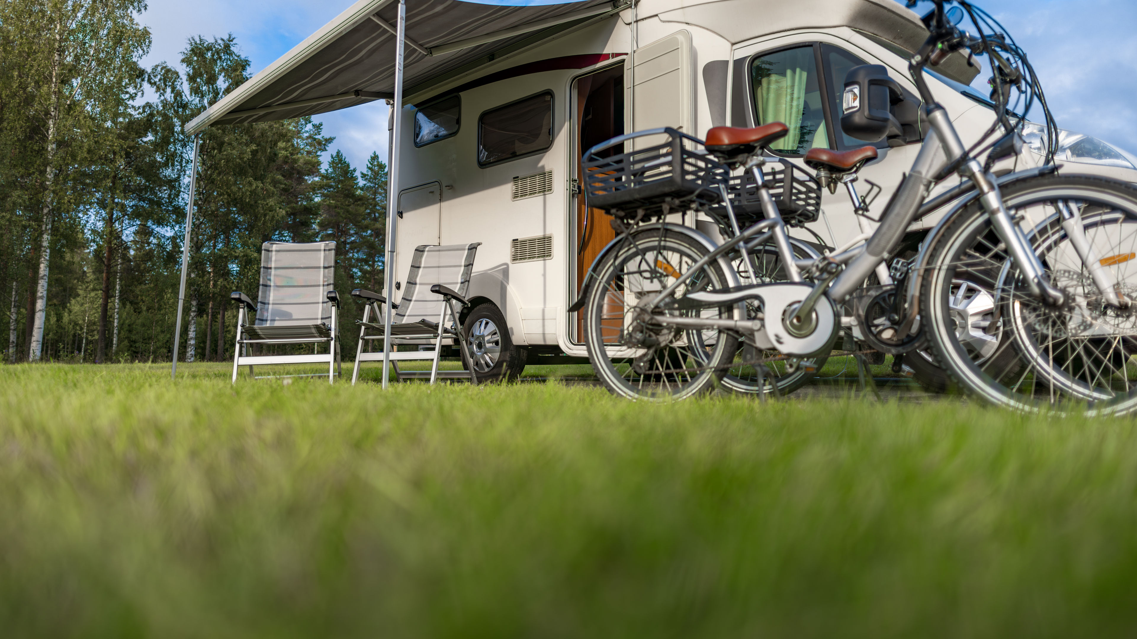 Two bicycles are parked in front of a motorhome.