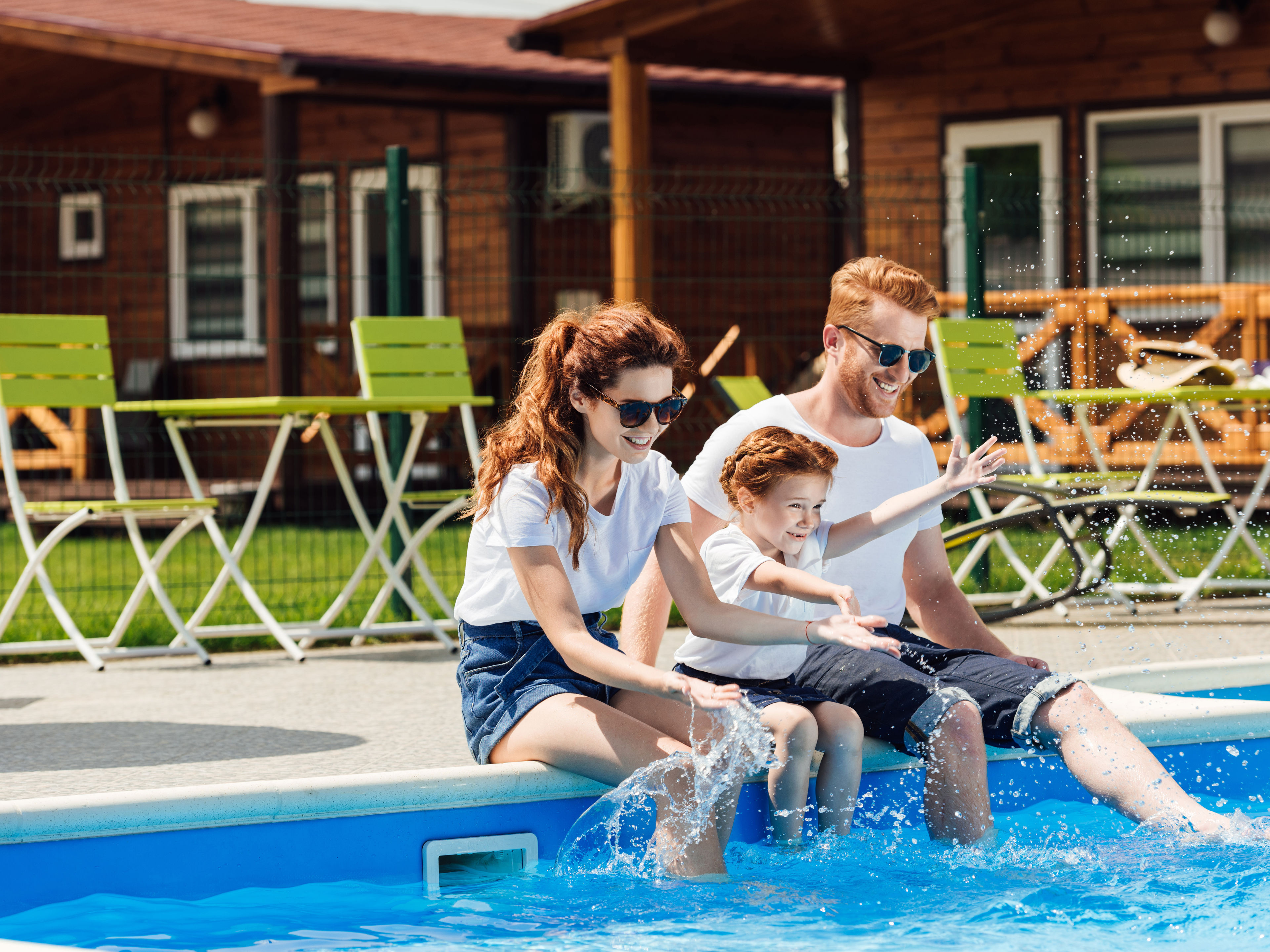 Young family sitting on poolside together